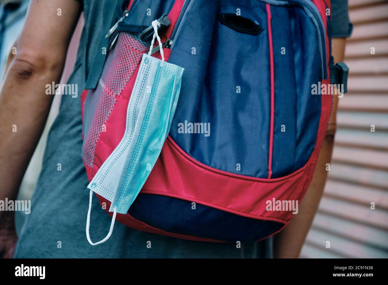 guardaroba di un giovane uomo in strada, in abbigliamento casual, con uno zaino con una maschera chirurgica appesa ad esso Foto Stock