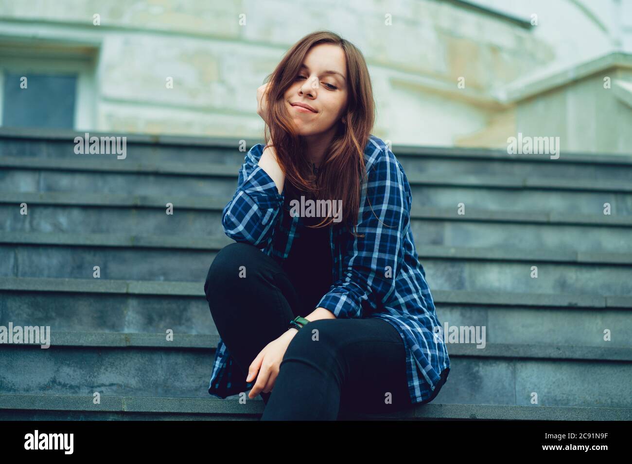 Giovane bella donna posa su scale di maniero. Donna sorridente adulta seduta sui gradini del palazzo. Foto Stock