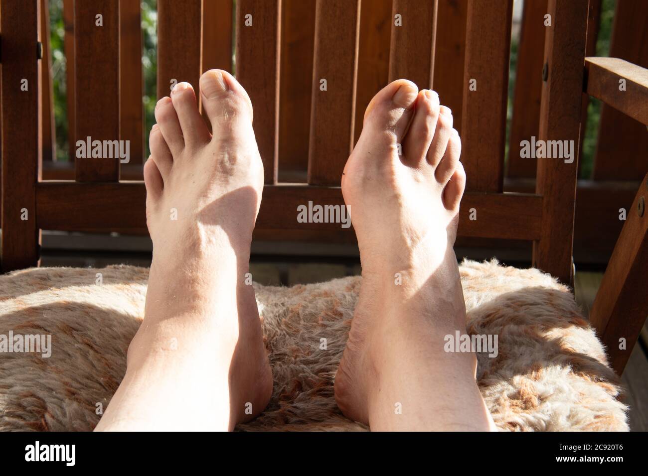 L'uomo sulla sedia a sdraio mette le gambe a piedi nudi in su Foto stock -  Alamy
