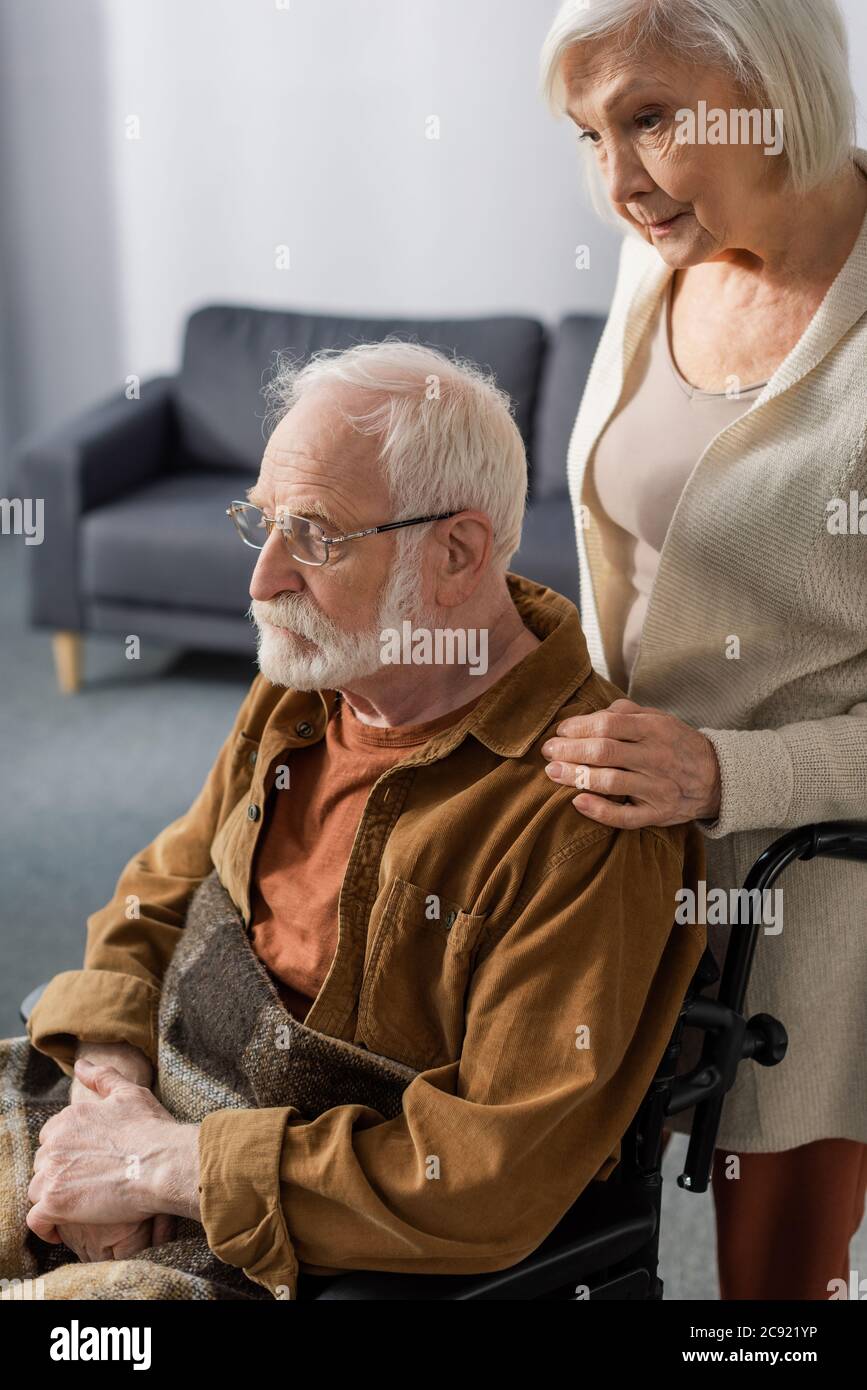 disprezzata donna anziana commovente di marito disabile, malato di demenza Foto Stock