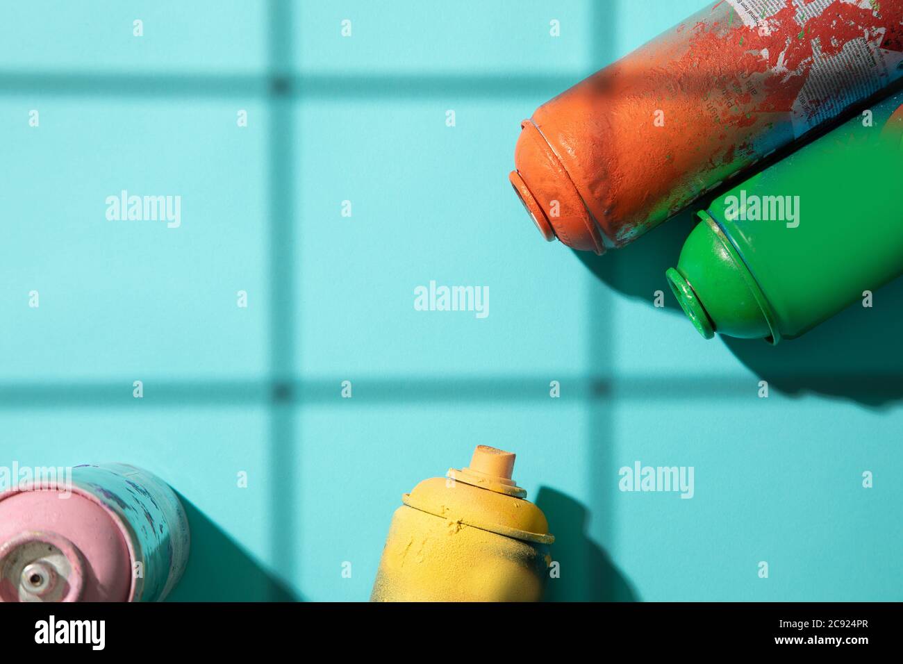 Un'altra vista dall'alto delle lattine di vernice spray usate su sfondo ciano con ombre della griglia e spazio libero per il testo Foto Stock