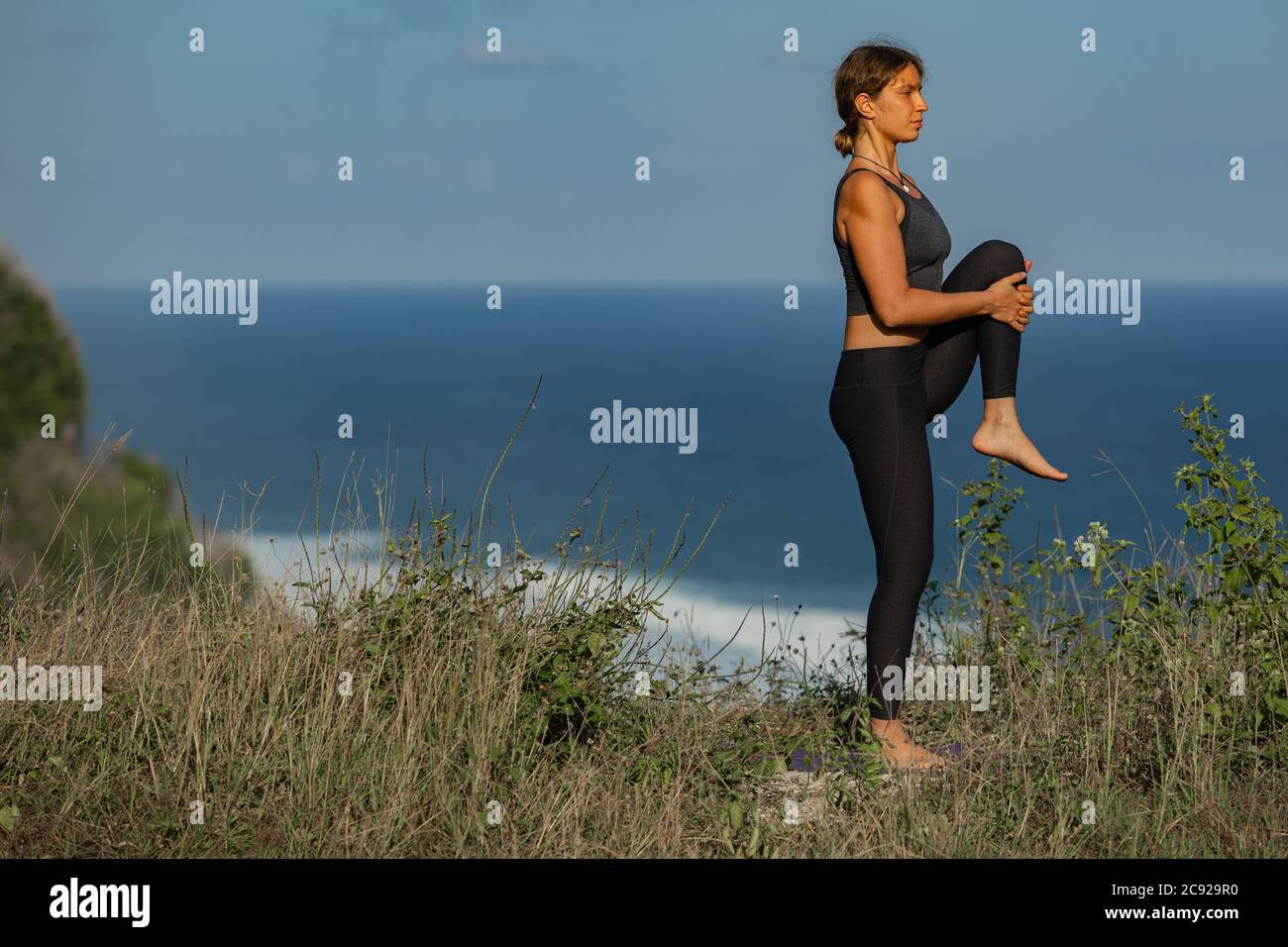 Giovane donna che fa yoga all'aperto con vista posteriore incredibile. Bali. Indonesia. Foto Stock