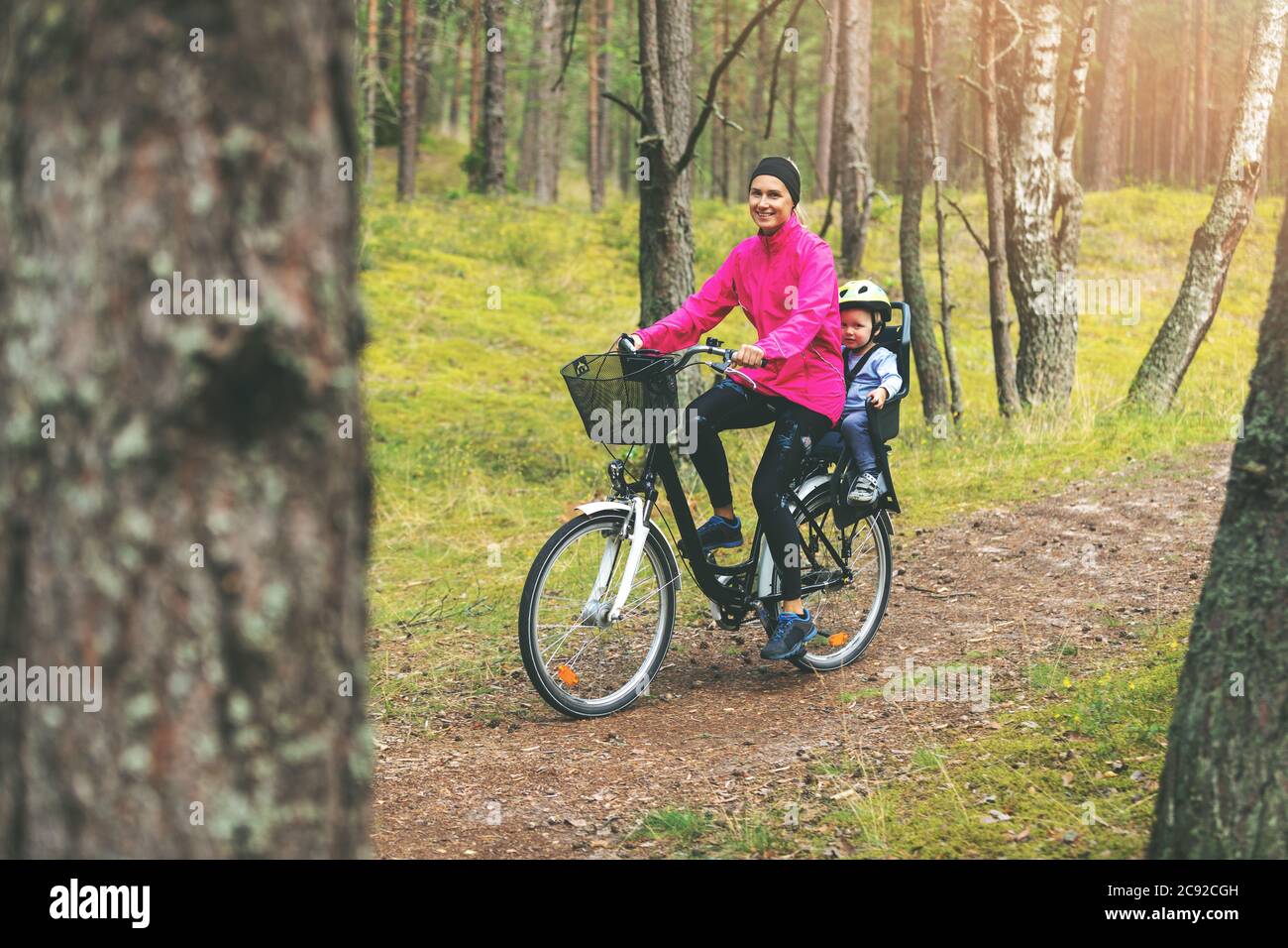 madre con figlio in bicicletta seggiolino per bambini in bicicletta su sentiero forestale Foto Stock