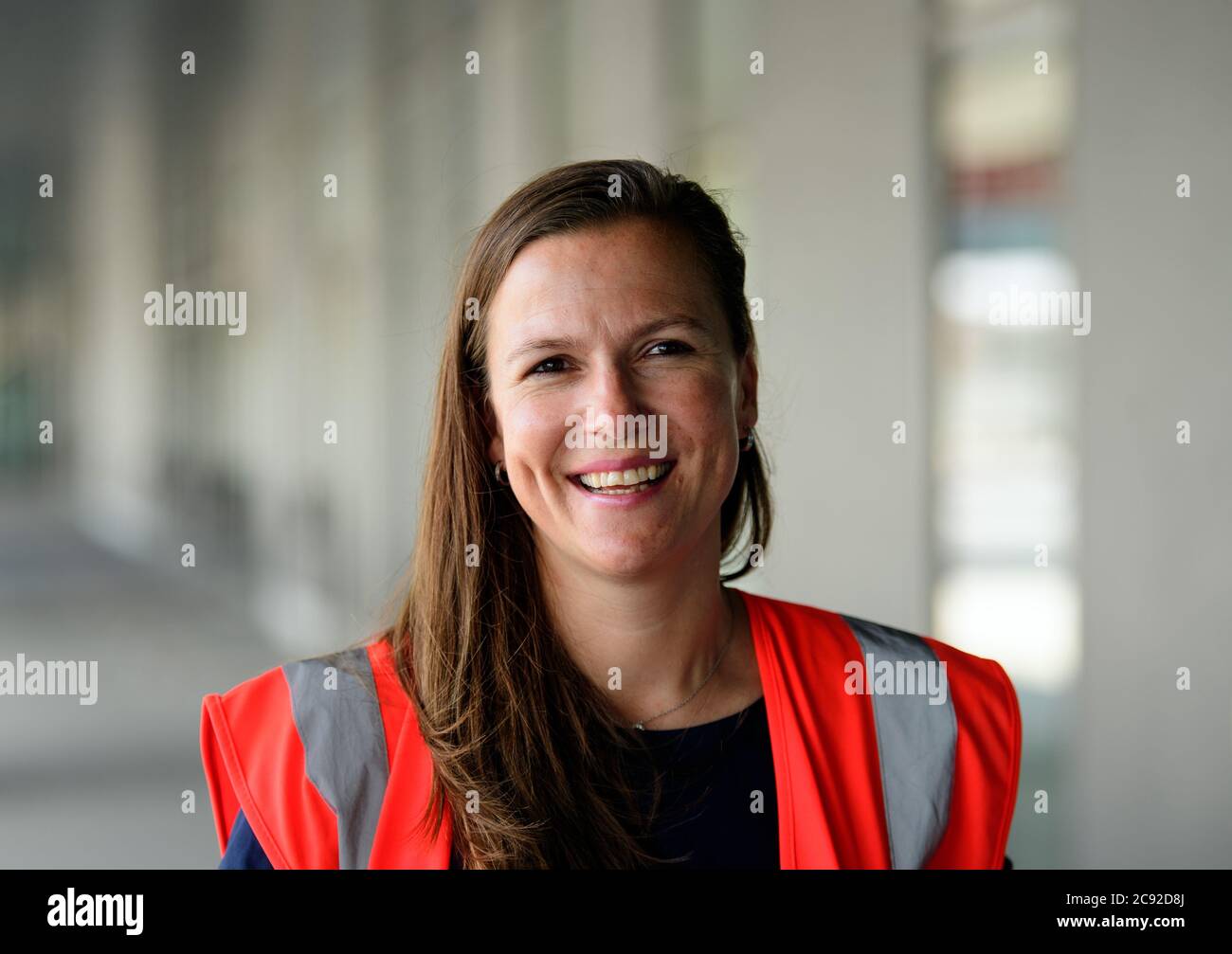 28 luglio 2020, Brandenburg, Schönefeld: Katy Krüger, Terminal Manager della Flughafen Berlin-Brandenburg GmbH, ride durante la prova con extra davanti al terminal dell'aeroporto di Berlino-Brandenburg (BER). Durante la seconda fase del trasferimento operazionale e di aeroporto (ORAT), circa 500 - 600 dipendenti e 400 volontari hanno provato le procedure standard per i passeggeri, dal check-in al controllo di sicurezza fino all'imbarco e al deboarding (arrivo). Foto: Soeren Stache/dpa-Zentralbild/dpa Foto Stock