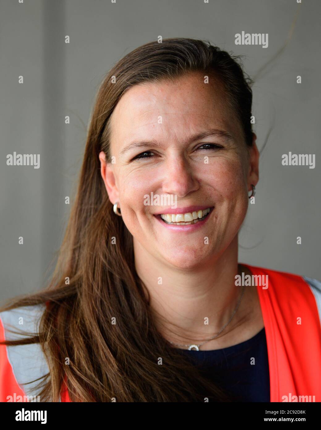 28 luglio 2020, Brandenburg, Schönefeld: Katy Krüger, Terminal Manager della Flughafen Berlin-Brandenburg GmbH, ride durante la prova con extra davanti al terminal dell'aeroporto di Berlino-Brandenburg (BER). Durante la seconda fase del trasferimento operazionale e di aeroporto (ORAT), circa 500 - 600 dipendenti e 400 volontari hanno provato le procedure standard per i passeggeri, dal check-in al controllo di sicurezza fino all'imbarco e al deboarding (arrivo). Foto: Soeren Stache/dpa-Zentralbild/dpa Foto Stock