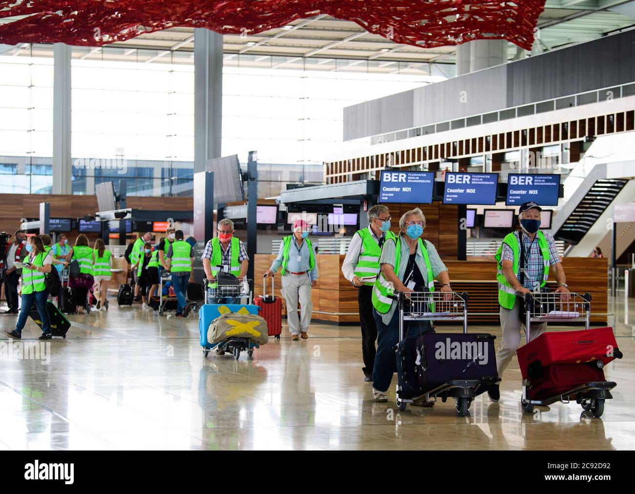 28 luglio 2020, Brandenburg, Schönefeld: Extra in giubbotti verdi ad alta visibilità vanno in una prova al Terminal 1 dell'aeroporto di Berlino-Brandeburgo (BER). Nella seconda fase del trasferimento operativo e di aeroporto (ORAT), circa 500 - 600 dipendenti aeroportuali e 400 volontari hanno provato le procedure standard per i passeggeri, dal check-in al controllo di sicurezza fino all'imbarco e al deboarding (arrivo). Foto: Soeren Stache/dpa-Zentralbild/dpa Foto Stock