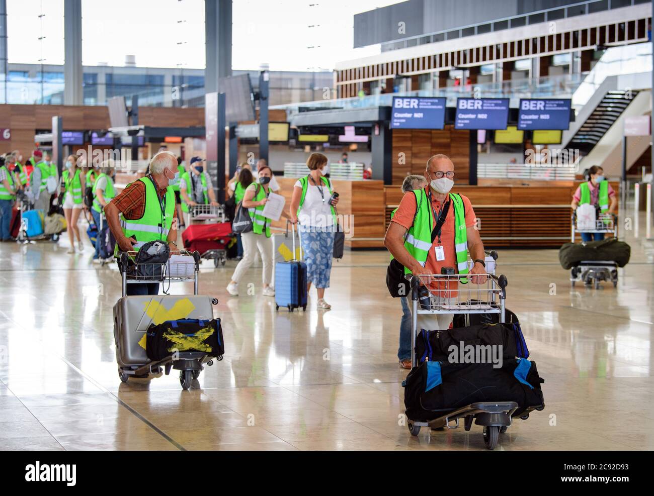 28 luglio 2020, Brandenburg, Schönefeld: Extra in giubbotti verdi ad alta visibilità vanno in una prova al Terminal 1 dell'aeroporto di Berlino-Brandeburgo (BER). Nella seconda fase del trasferimento operativo e di aeroporto (ORAT), circa 500 - 600 dipendenti aeroportuali e 400 volontari hanno provato le procedure standard per i passeggeri, dal check-in al controllo di sicurezza fino all'imbarco e al deboarding (arrivo). Foto: Soeren Stache/dpa-Zentralbild/dpa Foto Stock