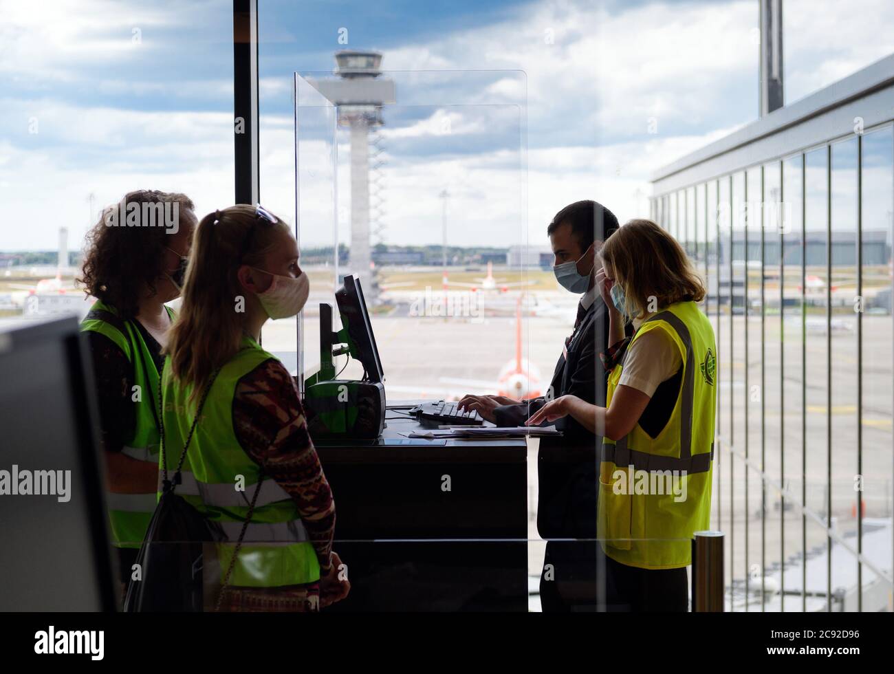 28 luglio 2020, Brandenburg, Schönefeld: Due comparatori (l) in giubbotti verdi ad alta visibilità sono in attesa di imbarco durante la prova al Terminal 1 dell'aeroporto capitale Berlino-Brandeburgo (BER). Nella seconda fase del trasferimento operazionale e di aeroporto (ORAT), circa 500 - 600 dipendenti e 400 volontari hanno provato le procedure standard per i passeggeri, dal check-in al controllo di sicurezza fino all'imbarco e al deboarding (arrivo). Foto: Soeren Stache/dpa-Zentralbild/dpa Foto Stock