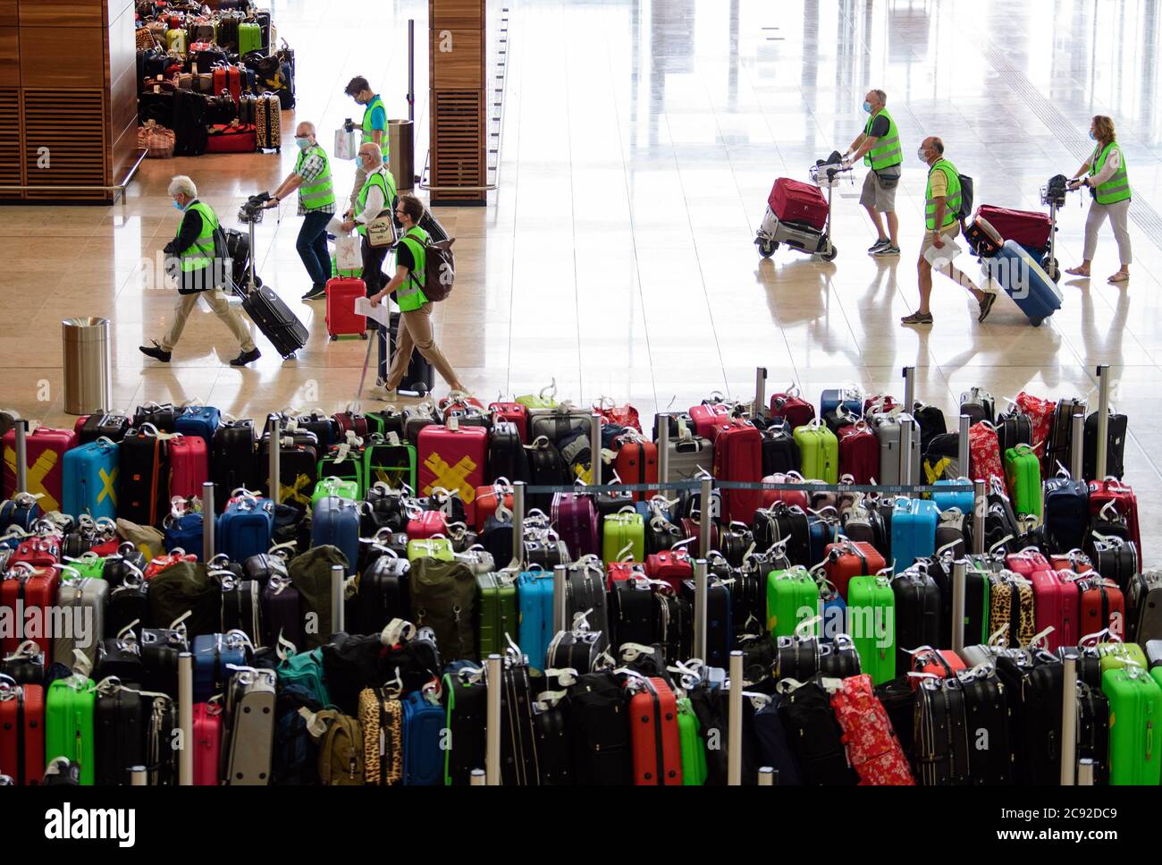 28 luglio 2020, Brandenburg, Schönefeld: Extra in giubbotti verdi ad alta visibilità vanno in una prova al Terminal 1 dell'aeroporto di Berlino-Brandeburgo (BER). Nella seconda fase del trasferimento operativo e di aeroporto (ORAT), circa 500 - 600 dipendenti aeroportuali e 400 volontari hanno provato le procedure standard per i passeggeri, dal check-in al controllo di sicurezza fino all'imbarco e al deboarding (arrivo). Foto: Soeren Stache/dpa-Zentralbild/dpa Foto Stock