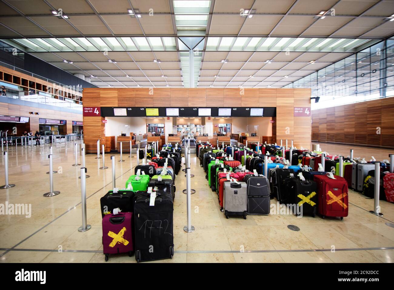 28 luglio 2020, Brandeburgo, Schönefeld: Durante la prova al Terminal 1 dell'aeroporto di Berlino-Brandeburgo (BER), le valigie sono parcheggiate di fronte al banco del check-in. Nella seconda fase del trasferimento operativo e di aeroporto (ORAT), circa 500 - 600 dipendenti e 400 volontari hanno provato le procedure standard per i passeggeri, dal check-in al controllo di sicurezza fino all'imbarco e al decollo (arrivo). Foto: Soeren Stache/dpa-Zentralbild/dpa Foto Stock