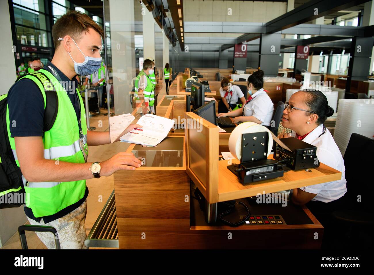 28 luglio 2020, Brandeburgo, Schönefeld: Gli extra in giubbotti verdi ad alta visibilità saranno esposti al banco del check-in del Terminal 1 dell'aeroporto di Berlino-Brandeburgo (BER). Nella seconda fase del trasferimento operativo e di aeroporto (ORAT), circa 500 - 600 dipendenti aeroportuali e 400 volontari hanno provato le procedure standard per i passeggeri, dal check-in al controllo di sicurezza, dall'imbarco al sbarco (arrivo). Foto: Soeren Stache/dpa-Zentralbild/dpa Foto Stock