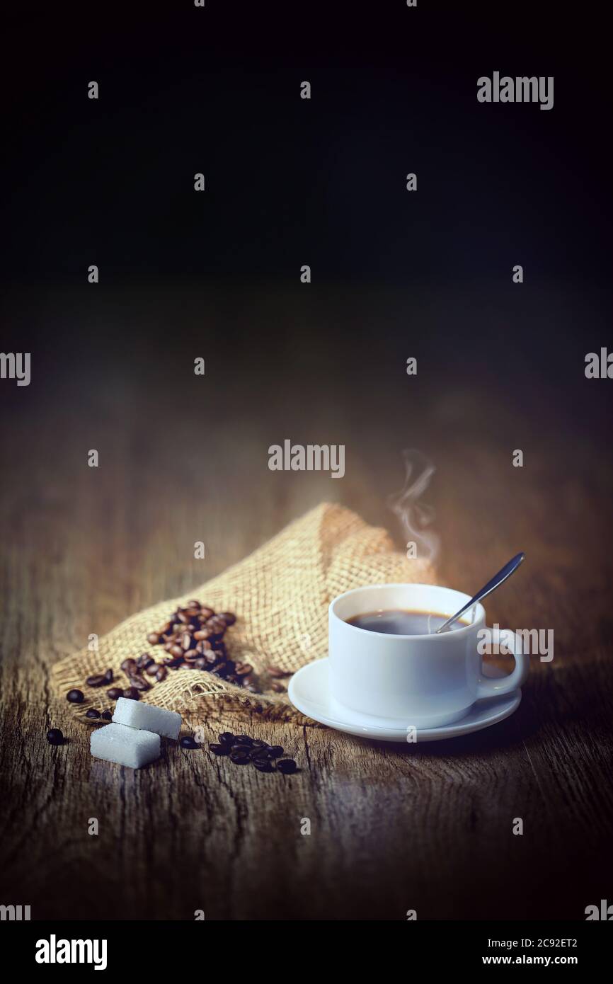 chicchi di caffè con tazza bianca, sfondo nero Foto Stock