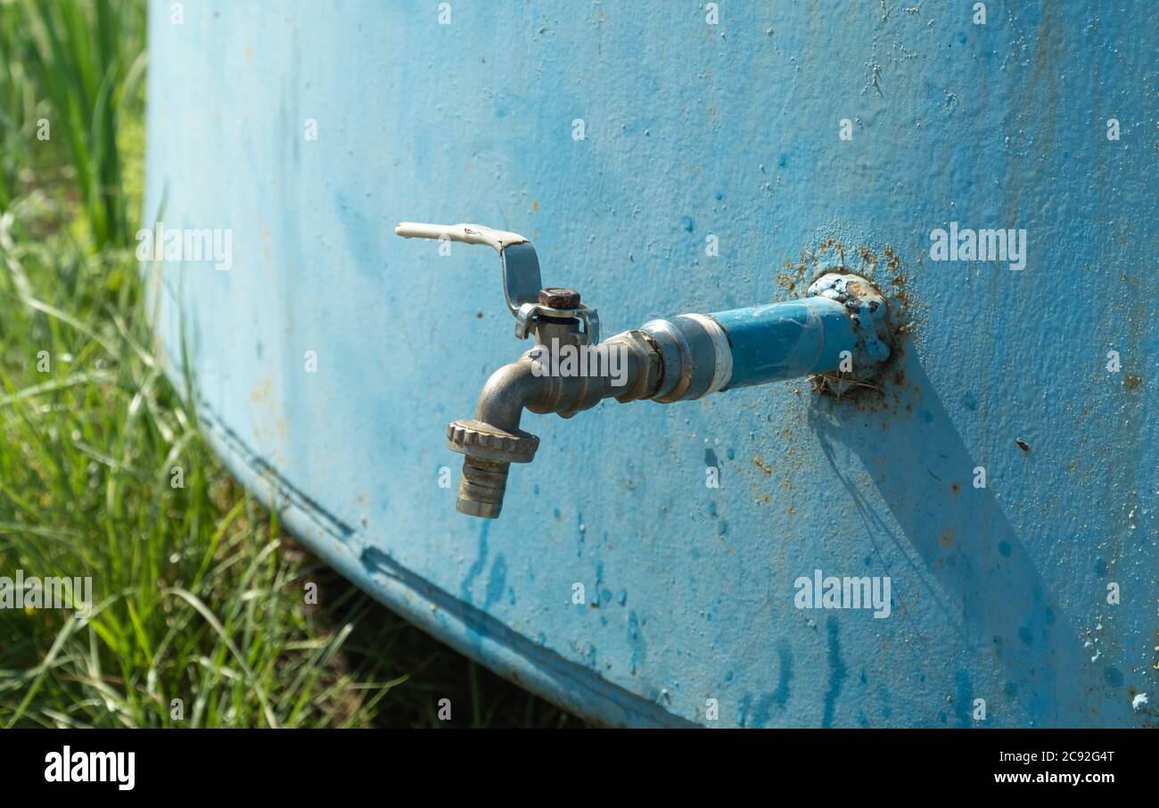 rubinetto d'acqua in un vecchio serbatoio di ferro sulla strada. acqua potabile. Foto Stock