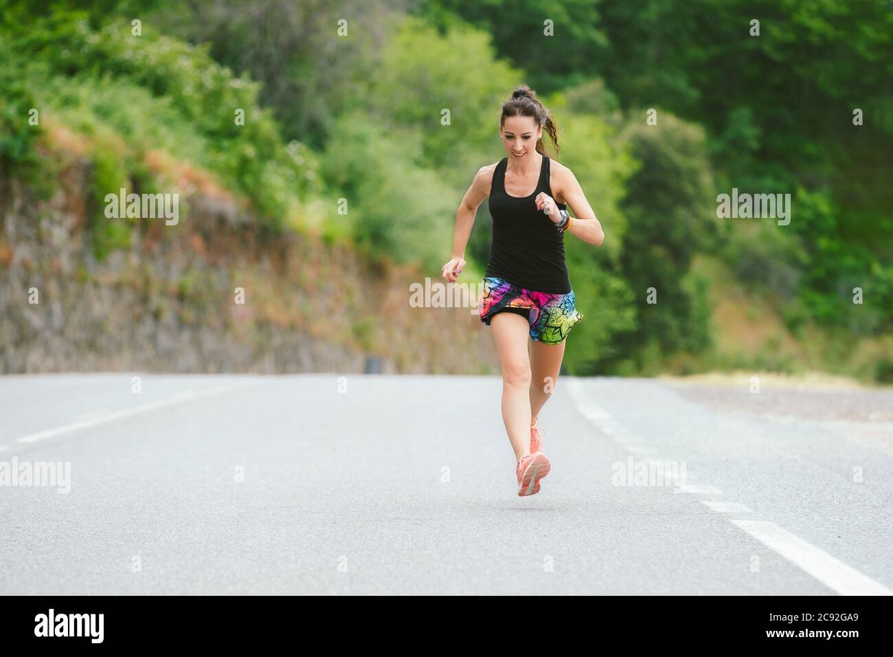 Donna con camicia nera e pantaloncini colorati per lo sport correre su  strada Foto stock - Alamy