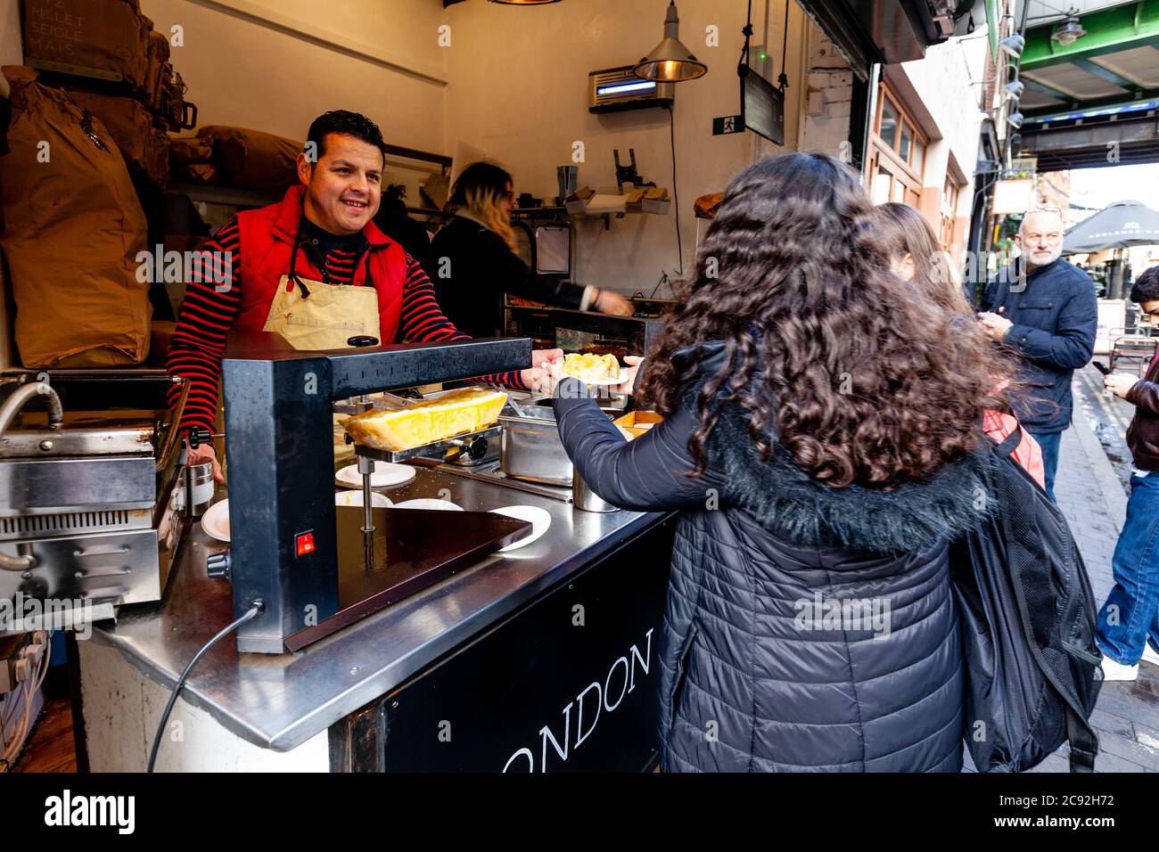Persone che acquistano cibo da UN negozio in Borough Market, Londra, Inghilterra. Foto Stock