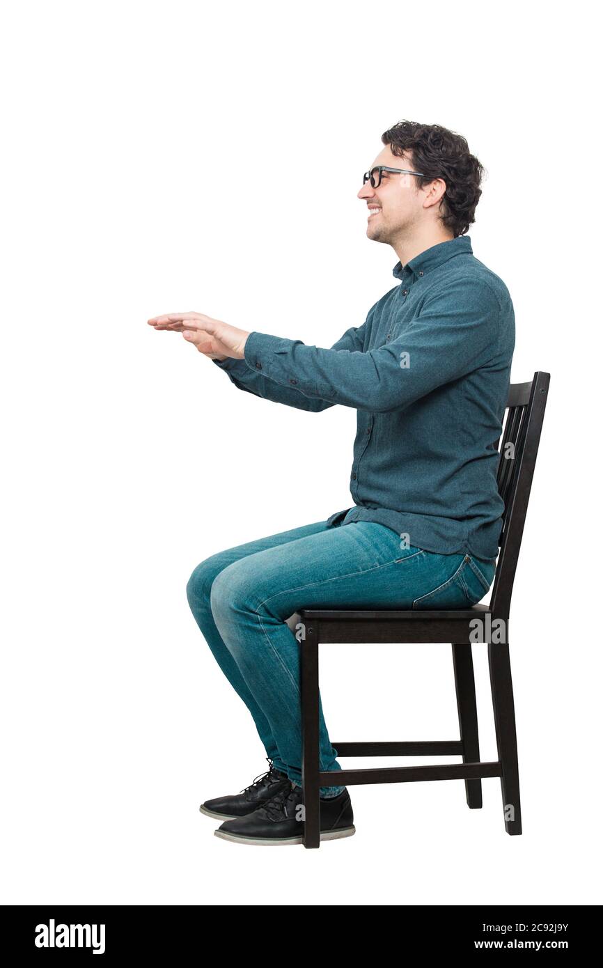 Vista laterale ritratto a lunghezza intera di allegro uomo casual seduto su una sedia mantiene le braccia aperte in avanti per un controllo medico isolato su sfondo bianco Foto Stock