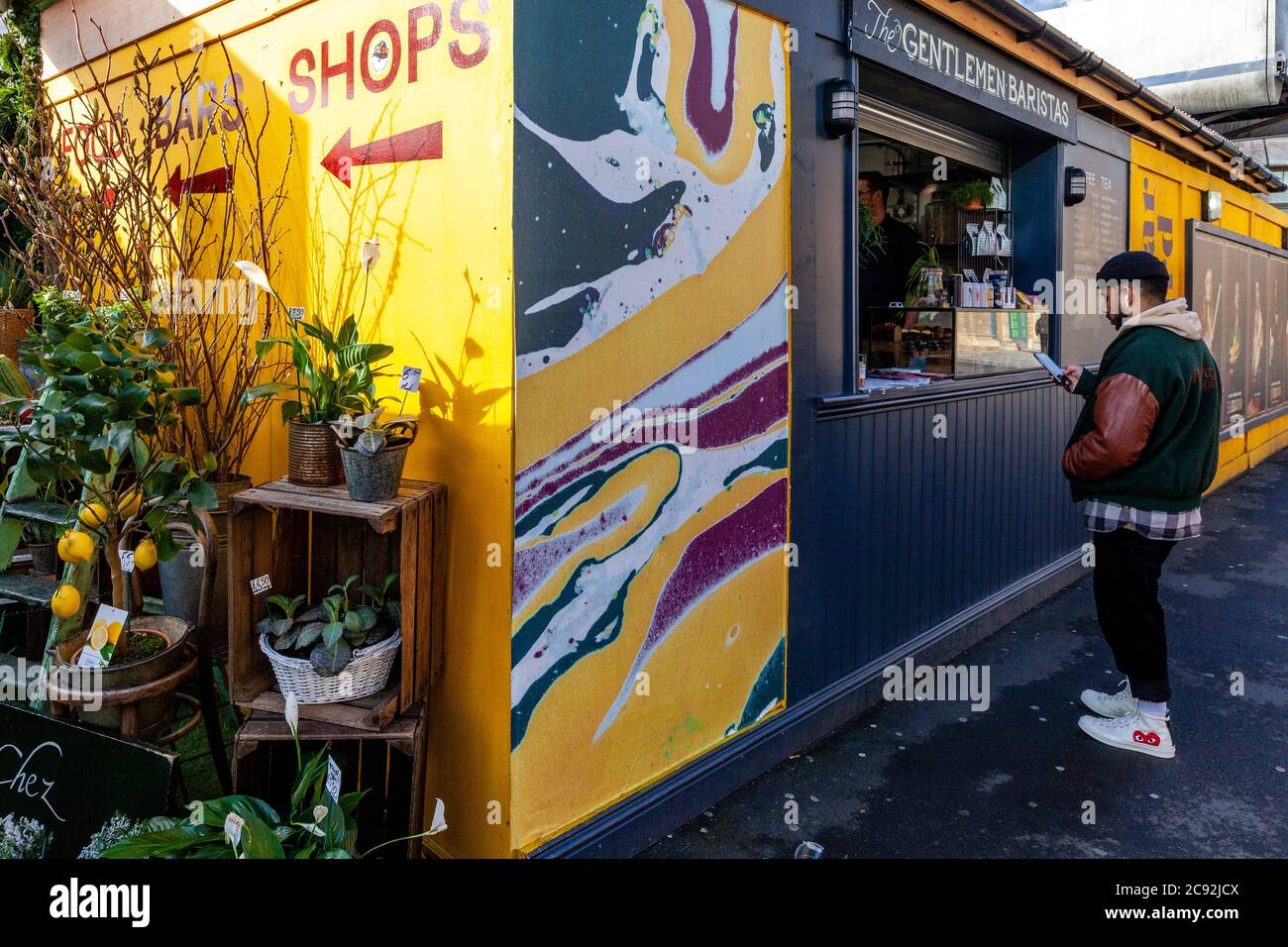 A Young Man Buying Coffee in un Coffee Shop a Aceto Yard, Londra, Inghilterra. Foto Stock