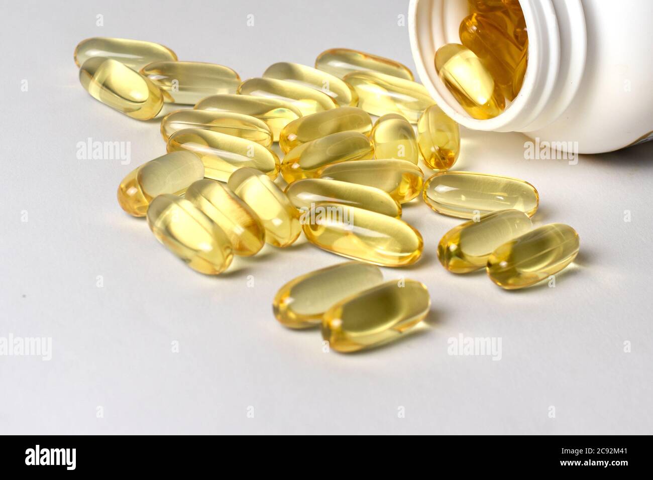 Capsule gialle omega-3 in un vaso bianco. I benefici per la salute dell'olio di pesce. Foto Stock