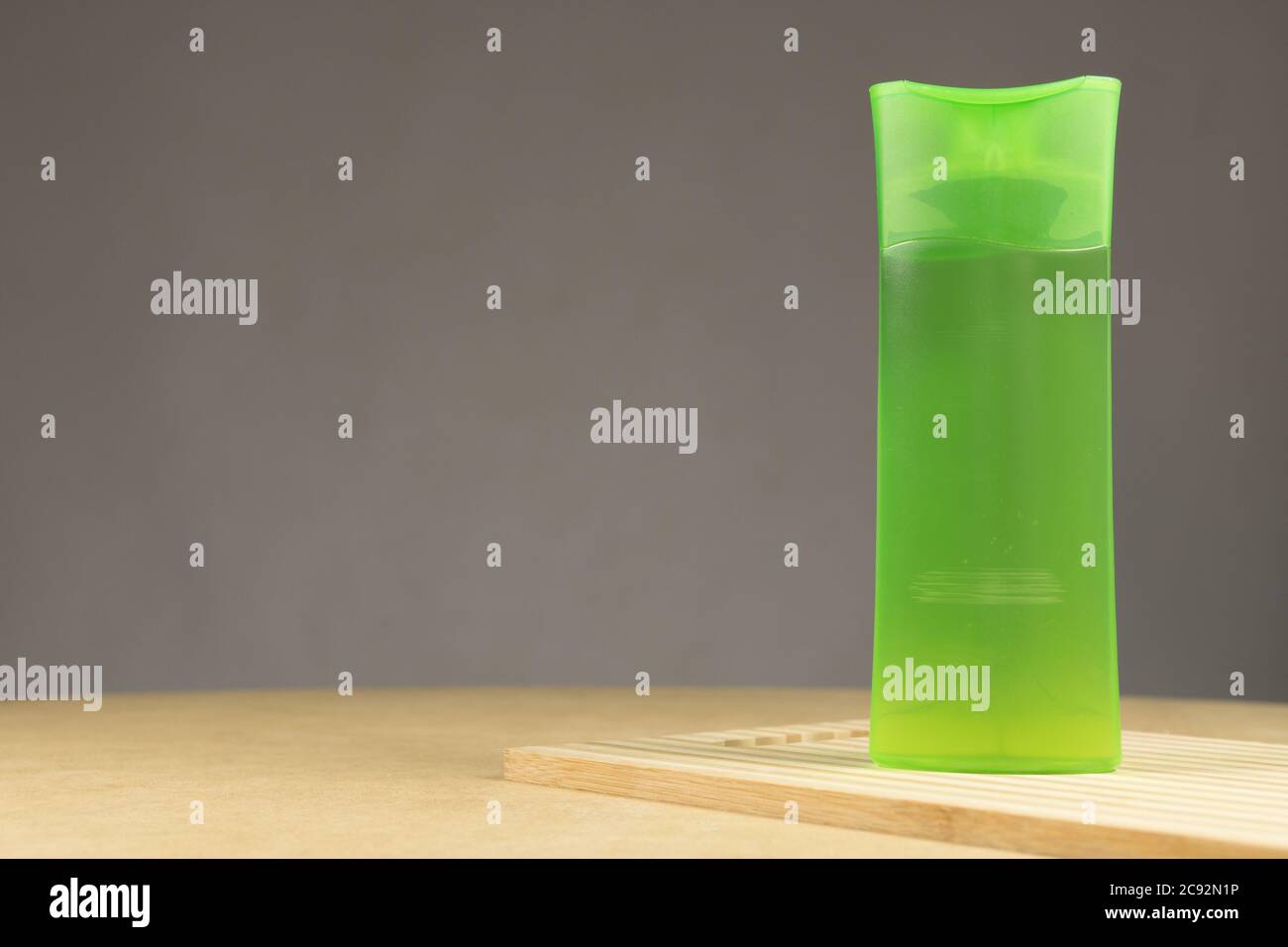 Tubo di plastica verde con shampoo isolato su sfondo grigio. Su un legno Foto Stock