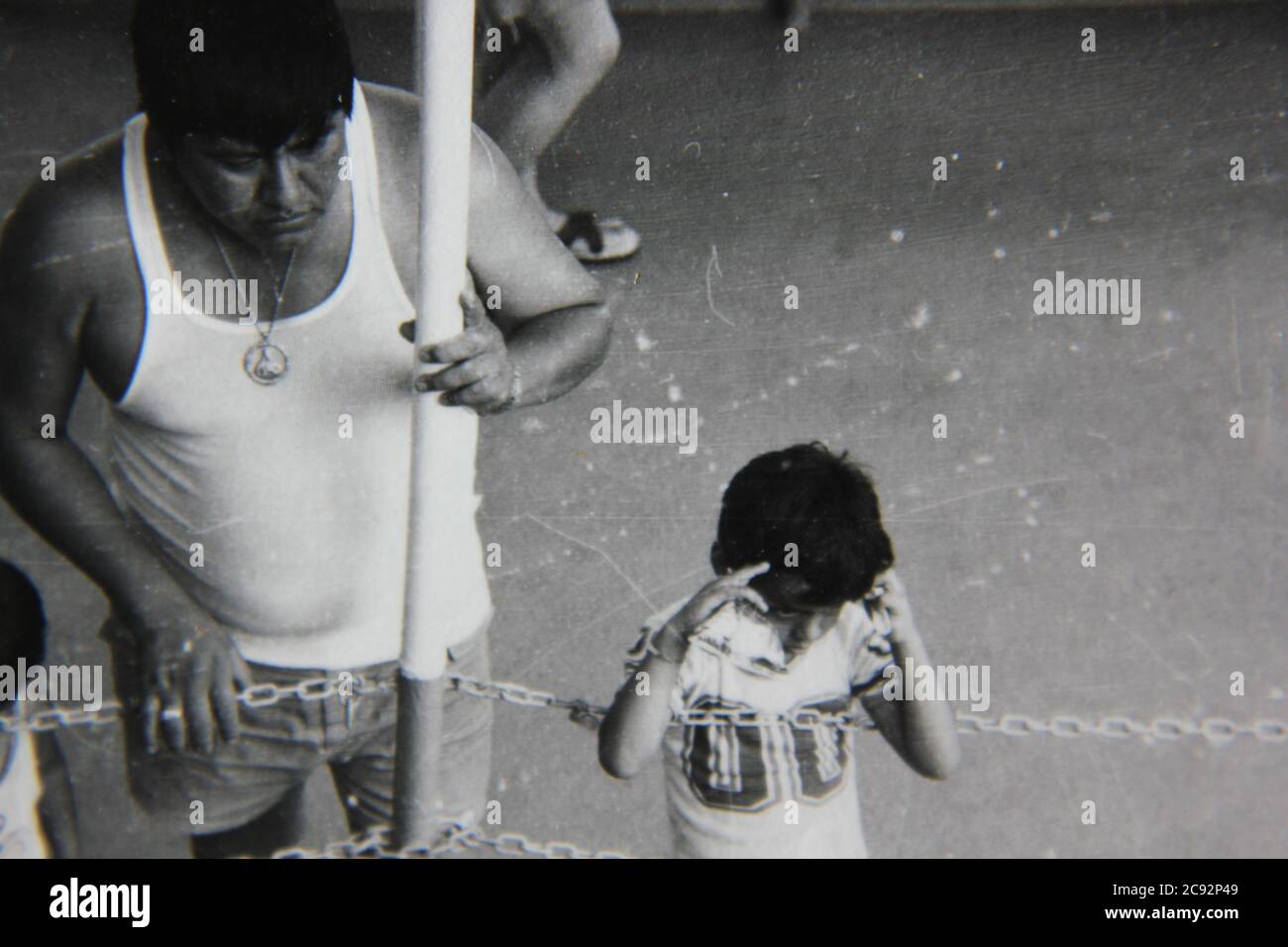Bella fotografia in bianco e nero degli anni '70 di un padre che tende alla sua giovane figlia. Foto Stock