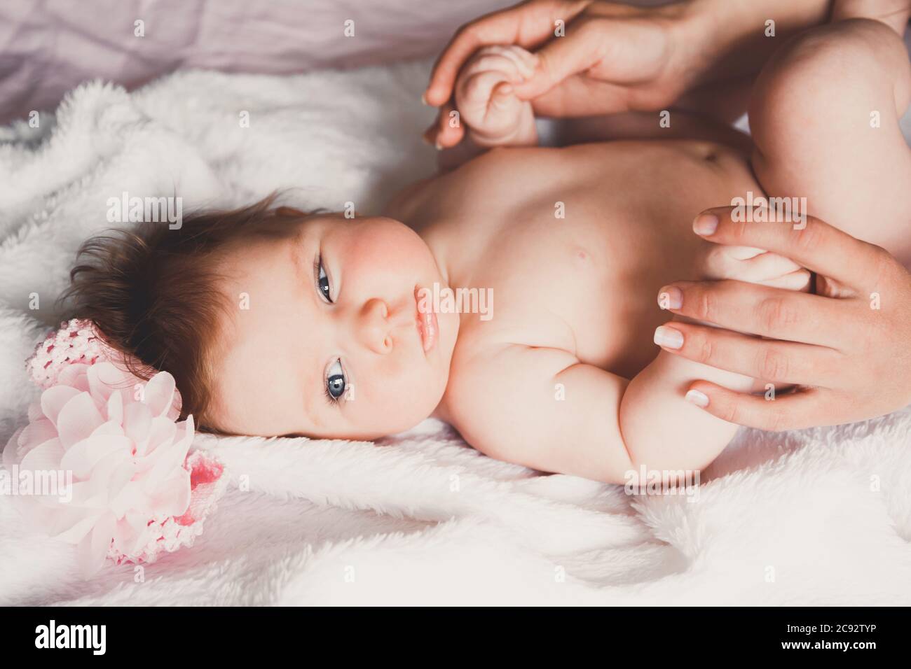 Primo piano ritratto di simpatica ragazza sorridente felice sdraiata sul letto. La madre sta tenendo il suo bambino neonato. Figlia piccola e mamma. Foto Stock
