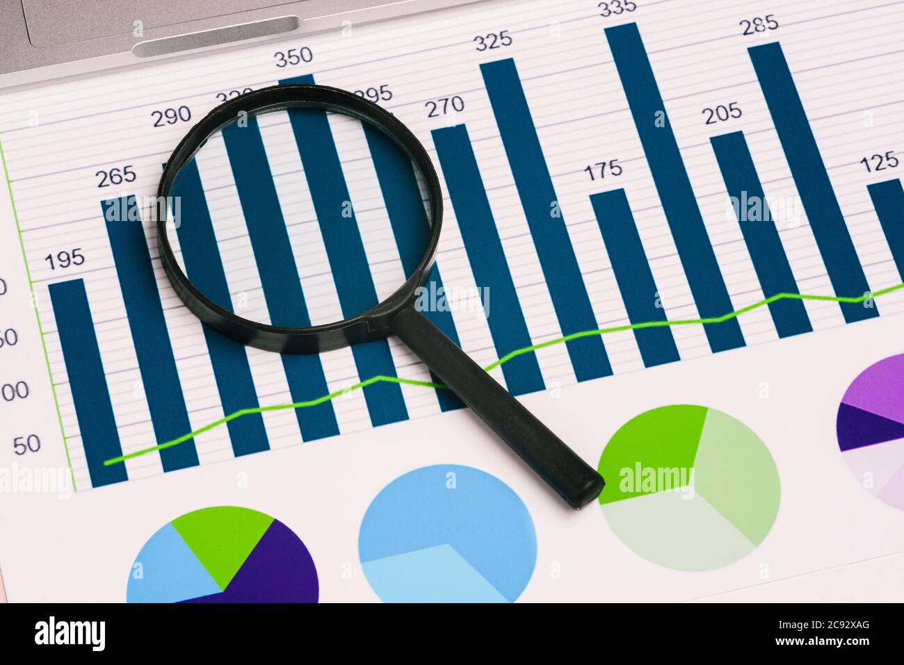 Lente di ingrandimento e diagrammi in vetro sul desktop. Concetto aziendale e analisi dei dati. Una vista dall'alto di un layout piatto. Foto Stock