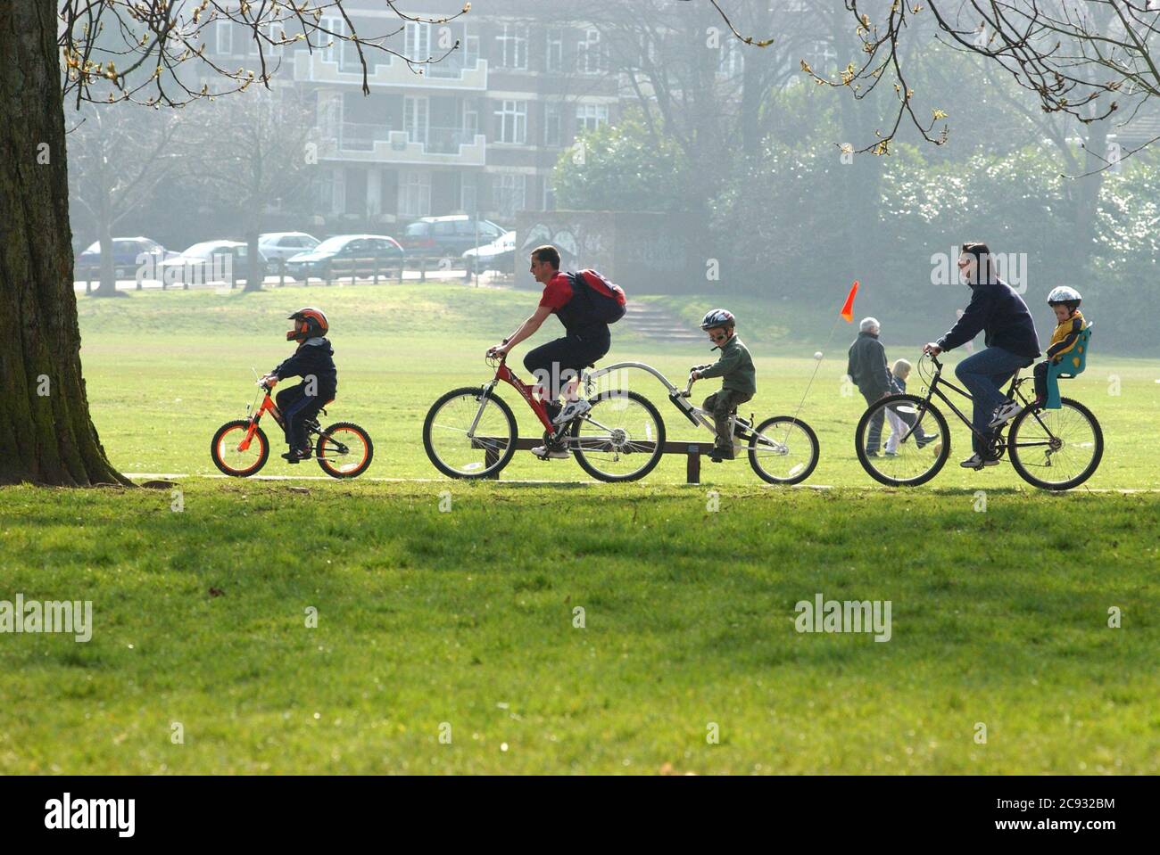 Un pomeriggio non così pigro domenica al sole a Pontcanna Fields, Cardiff, Galles oggi come una famiglia va in bicicletta. Foto Stock