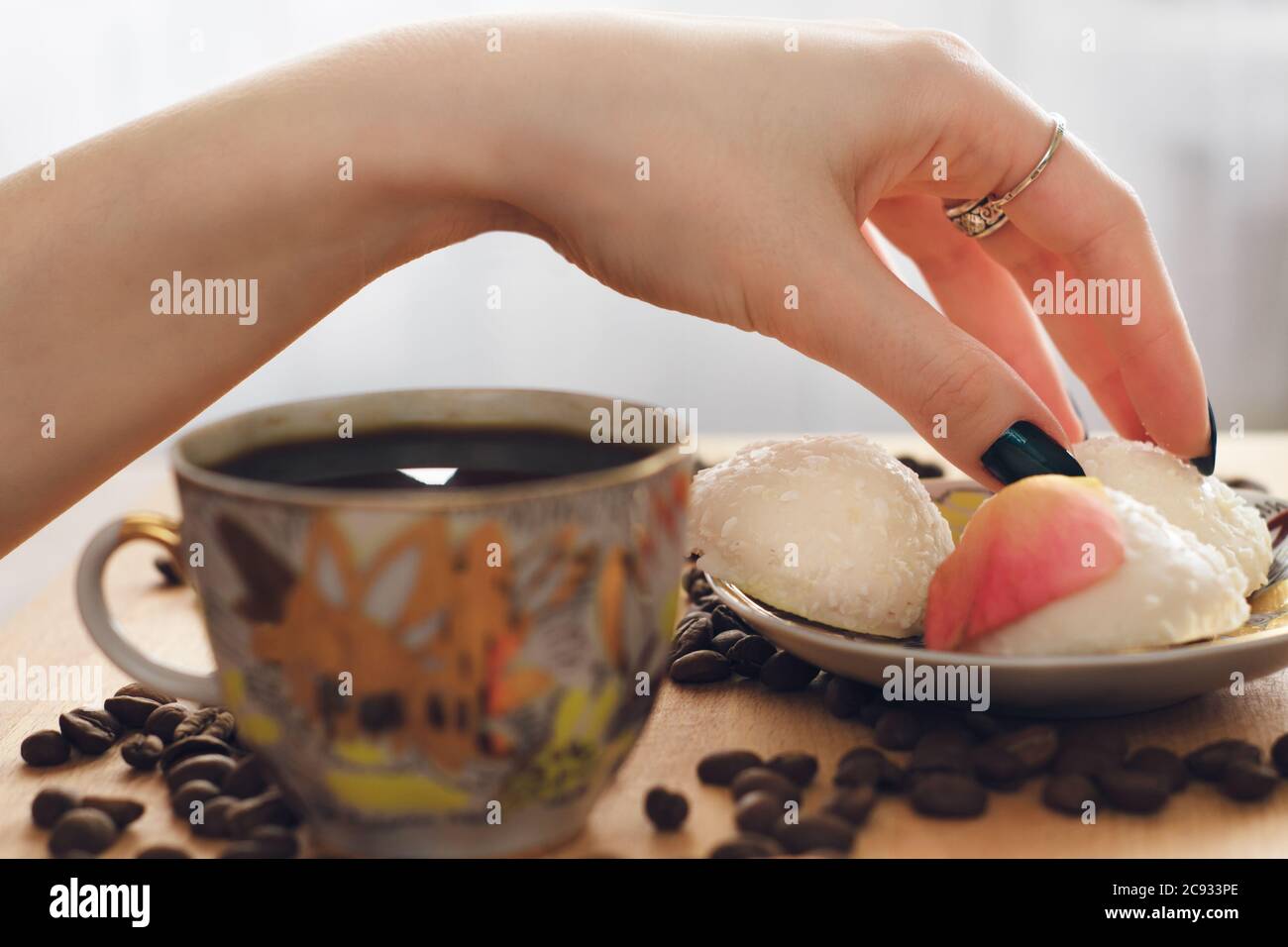 mano delicata e femminile, prende i biscotti dell'aria con il caffè, al mattino Foto Stock