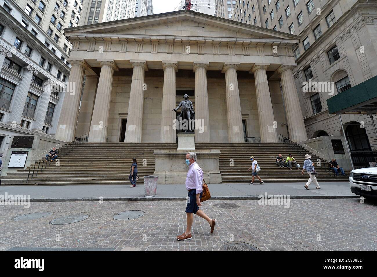 Un uomo cammina oltre la Federal Hall e la statua del presidente George Washington lungo Wall Street, dopo che i repubblicani del Senato hanno annunciato un pacchetto di stimoli da 1 trilione di dollari il giorno prima, New York, NY, 28 luglio 2020. I repubblicani hanno annunciato la legge "Heals" (Health, Economic Assistance Liability Protection & Schools Act), con un assegno di stimolo di 1,200 dollari per ogni contribuente fiscale, 2,400 dollari per i coniugi/filer, sussidi di disoccupazione al 70% dei salari, prestiti del programma di protezione dei salari e 105 miliardi di dollari per le scuole. (Anthony Behar/Sipa USA) Foto Stock