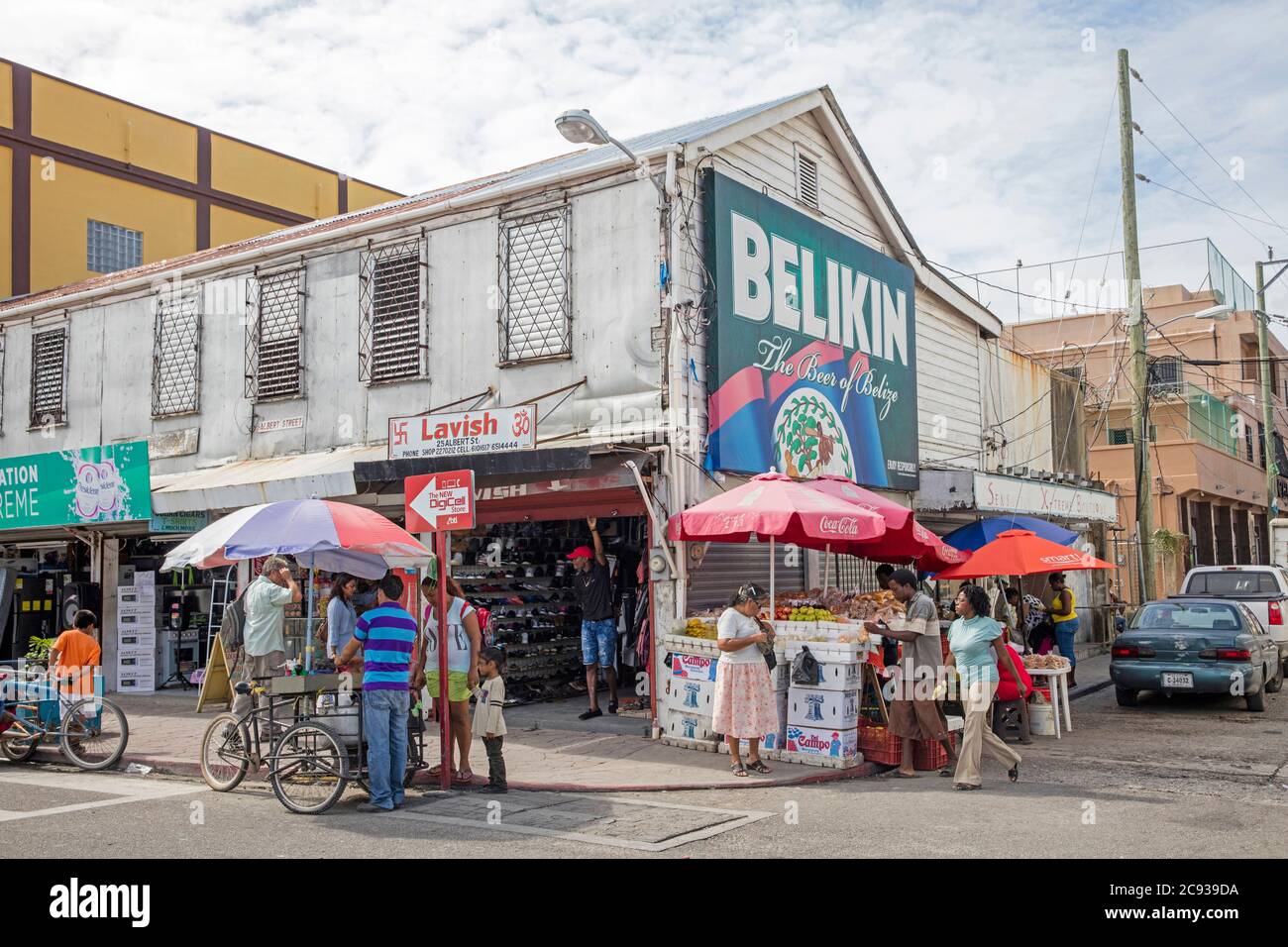 I clienti che fanno acquisti in una strada trafficata con negozi e bancarelle di vendita di frutta a Belize City, Caraibi, America Centrale Foto Stock