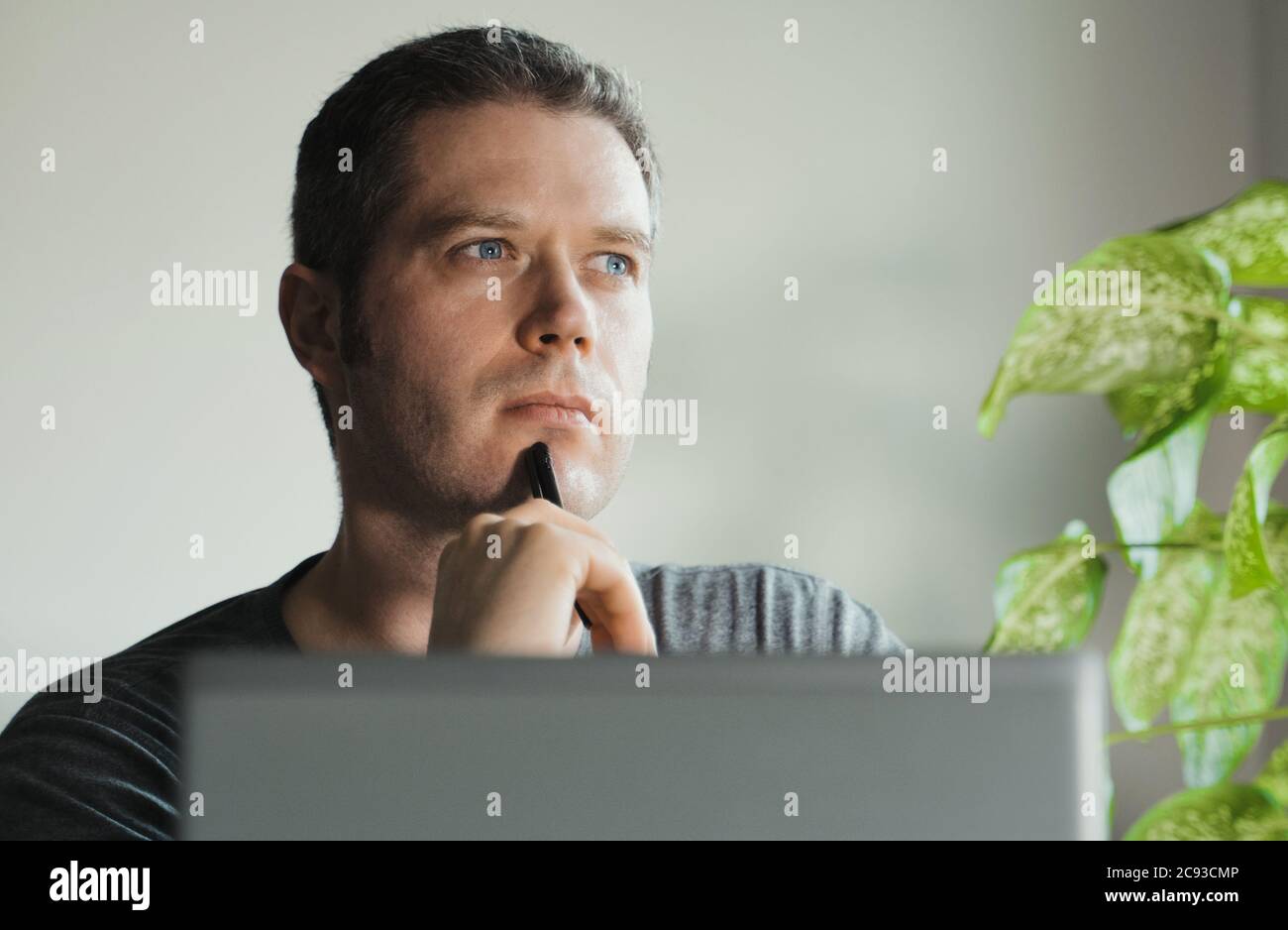 Bell'uomo pensieroso davanti al suo laptop in ufficio. Foto Stock