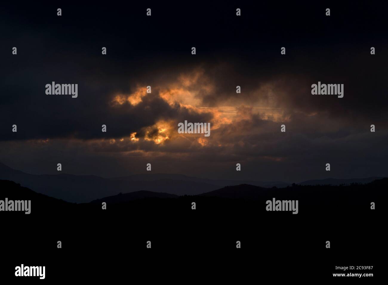 Nuvole rosse in un paesaggio di montagna oscuro in notturna Foto Stock