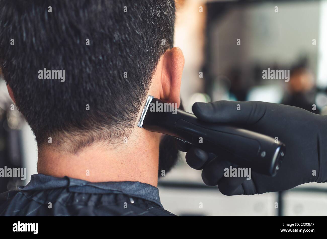 Barbiere taglio capelli su collo e nuca di uomo in barbiere con strumento  professionale regolacapelli. Rifinitore elettrico per tagliare i capelli  sulla pelle del cliente. Primo piano Foto stock - Alamy