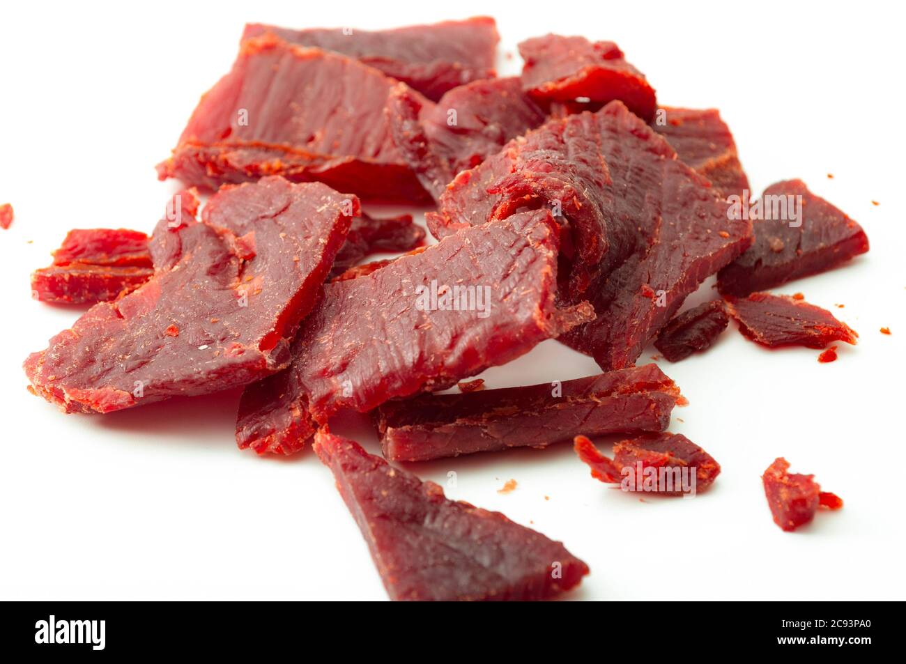 Dieta ad alta proteina e cibo che è alto nel tema di concetto di sodio e sale con primo piano su strisce di carne di manzo a scatti isolati su sfondo bianco Foto Stock