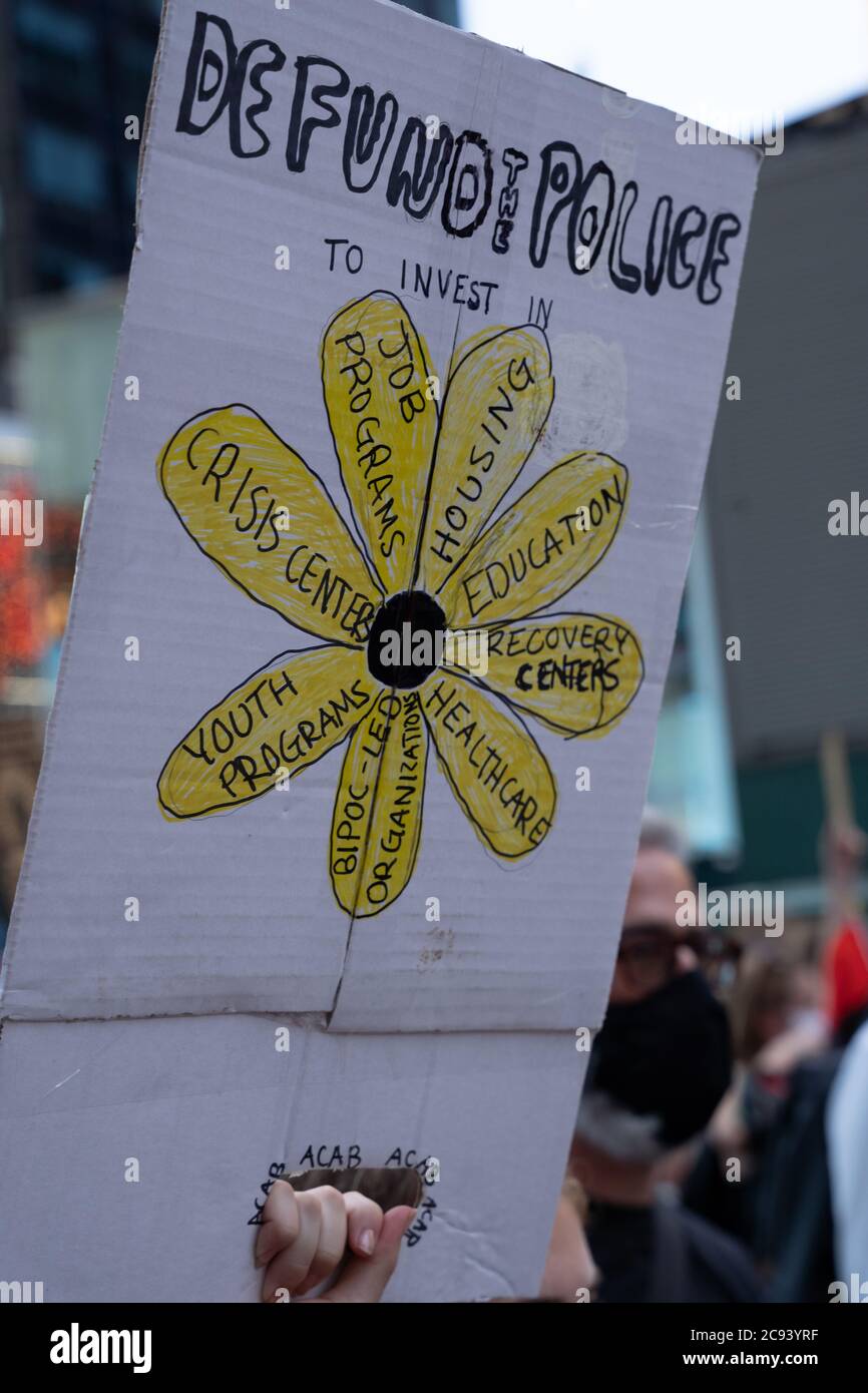 Black Womans/Womxn March Black Lives Matter protesta - Defund the Police Sign with Yellow flower Foto Stock