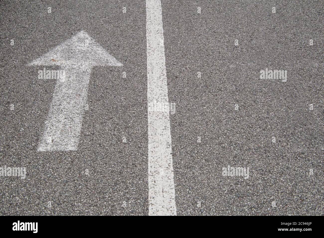 Freccia con una linea, vernice bianca su asfalto a grana piccola. Foto Stock