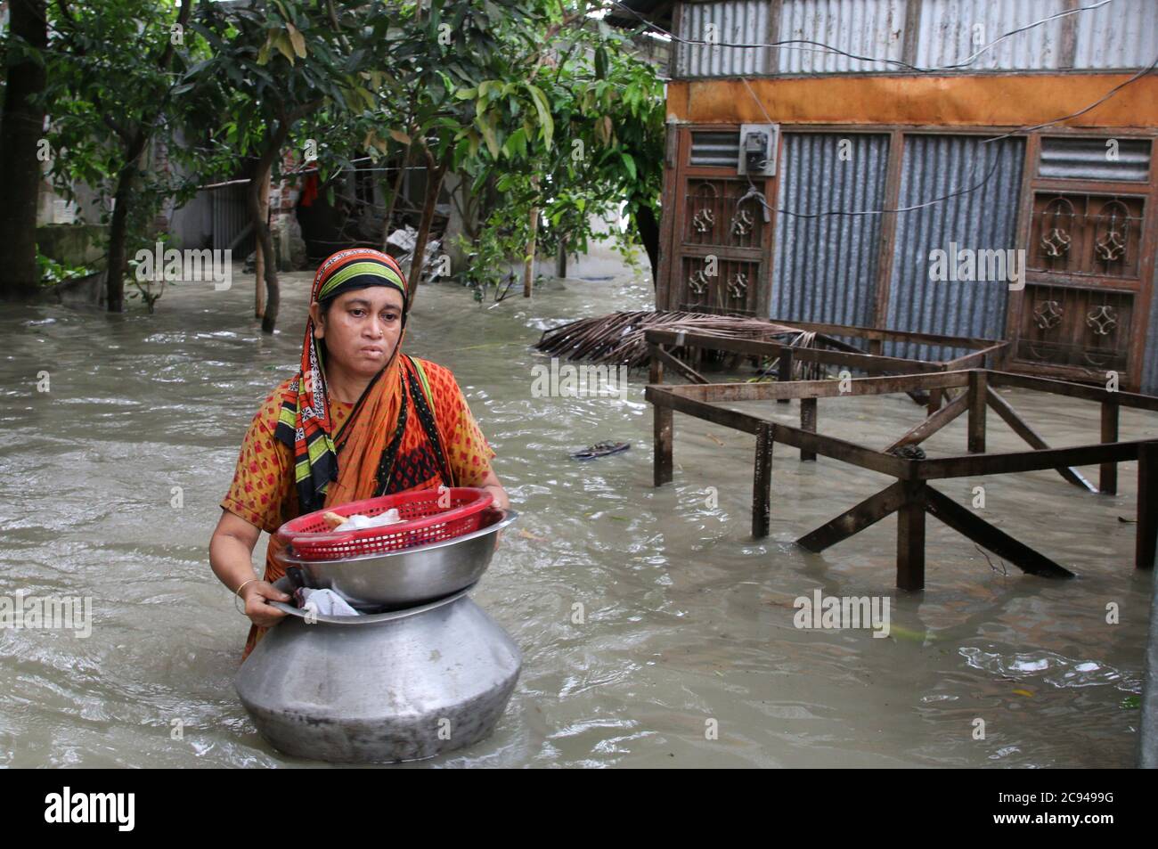 Un'inondazione ha colpito le donne che hanno portato i suoi articoli domestici in un luogo sicuro durante il postmath.un terzo del Bangladesh è sotto l'acqua dopo alcune delle piogge più pesanti in un decennio, lasciando più di 3 milioni di persone colpite da case e strade nei villaggi allagati, Hanno detto i funzionari del Centro di previsione e allarme delle inondazioni (FFWC). Foto Stock