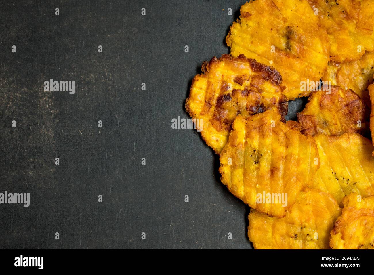 Tagliata gialla fritta banana latina su un tavolo nero Foto Stock