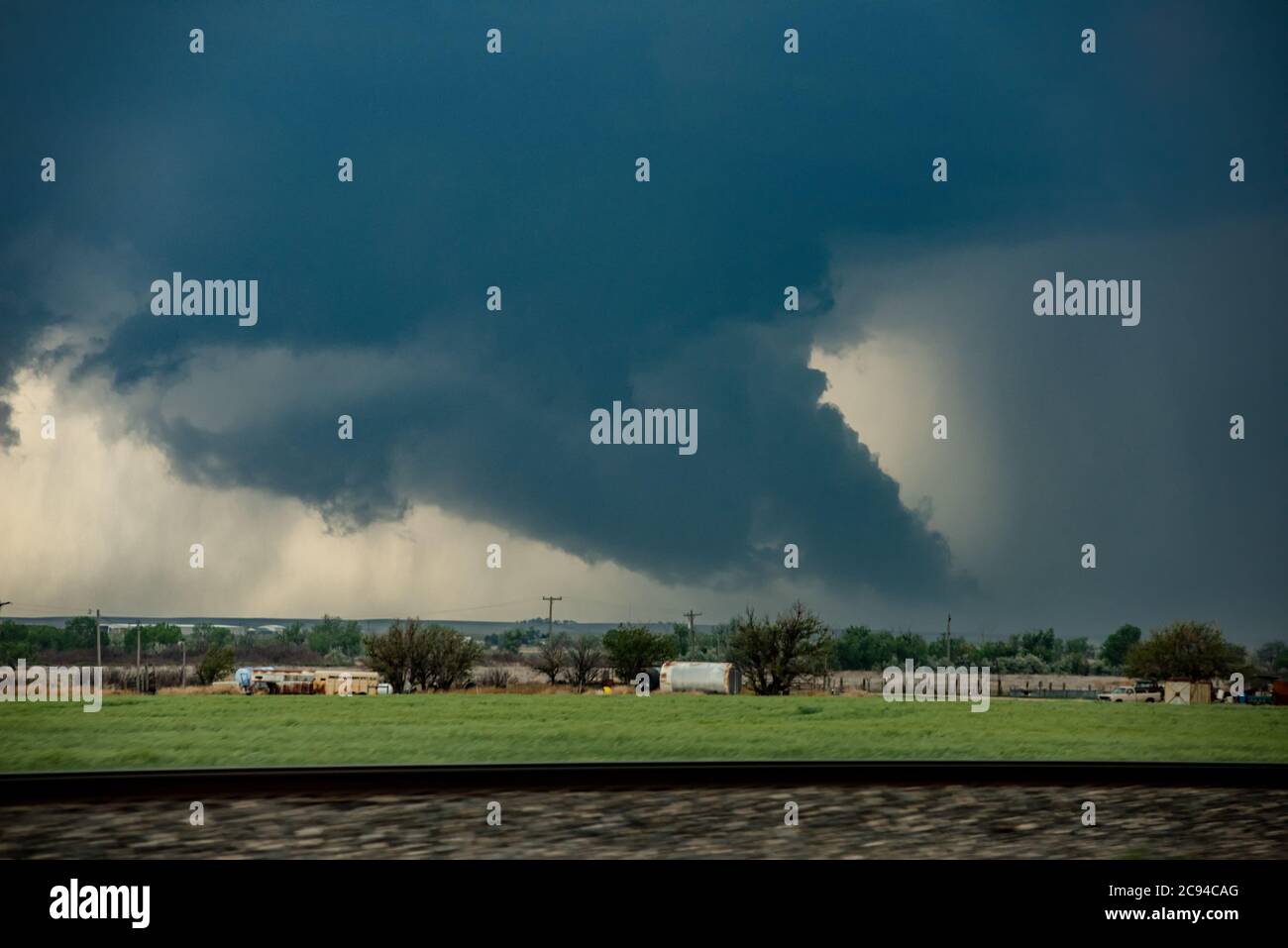 Un gigantesco tornado si muove velocemente lungo un'autostrada verso una città che si trova a chilometri circa di distanza. Foto Stock