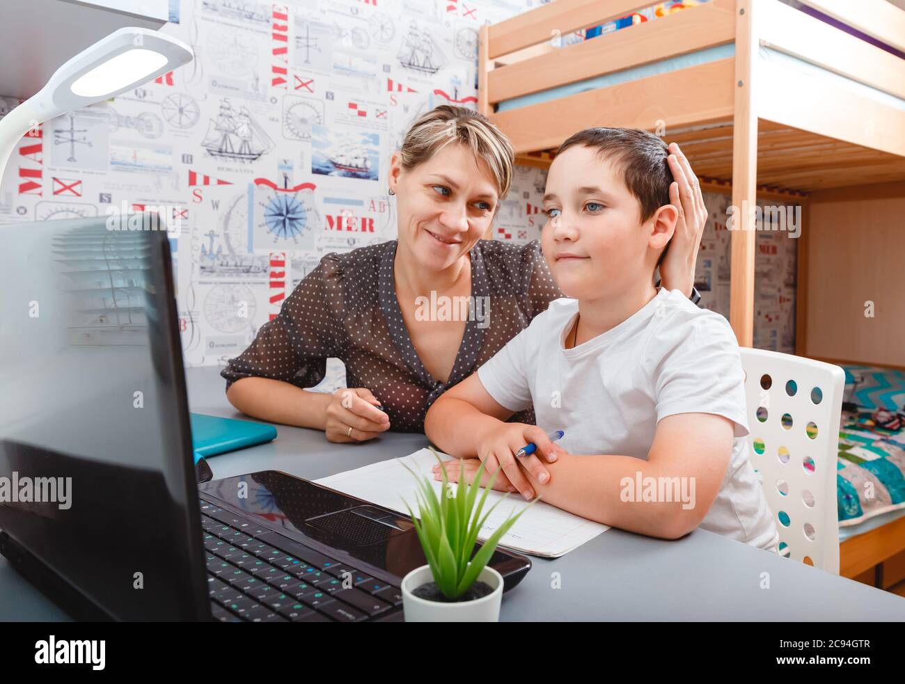 Il ragazzo di scuola grazioso sta studiando la matematica durante la sua lezione in linea a casa Foto Stock