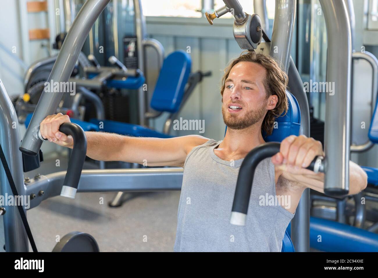 Uomo che fa esercizi sul petto su macchina verticale da banco Foto Stock