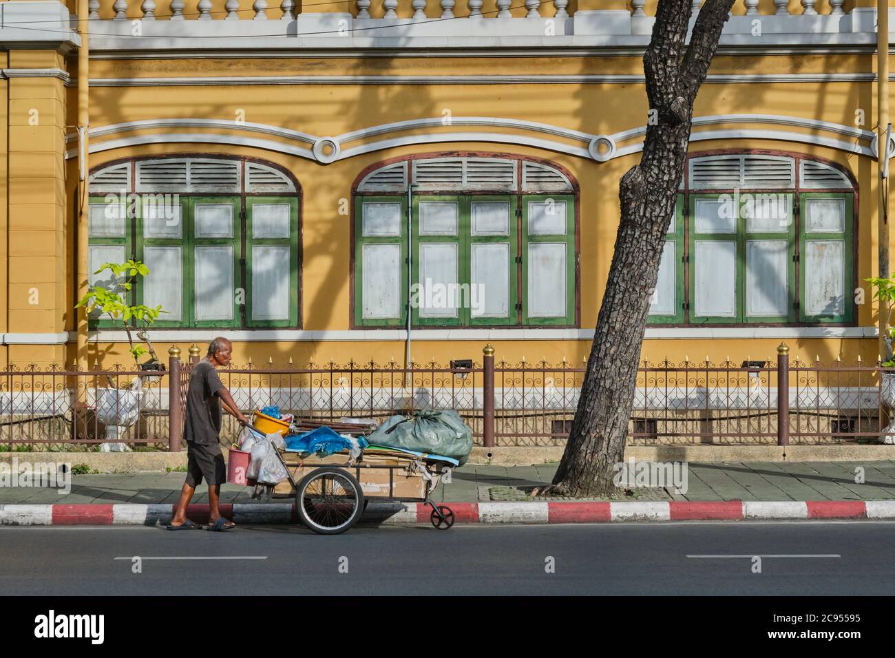 Un venditore di strada con il suo carretto passa la storica scuola Suan Gularb Witthalayai, fondata nel 1882 e costruita in stile europeo; Bangkok, Thailandia Foto Stock