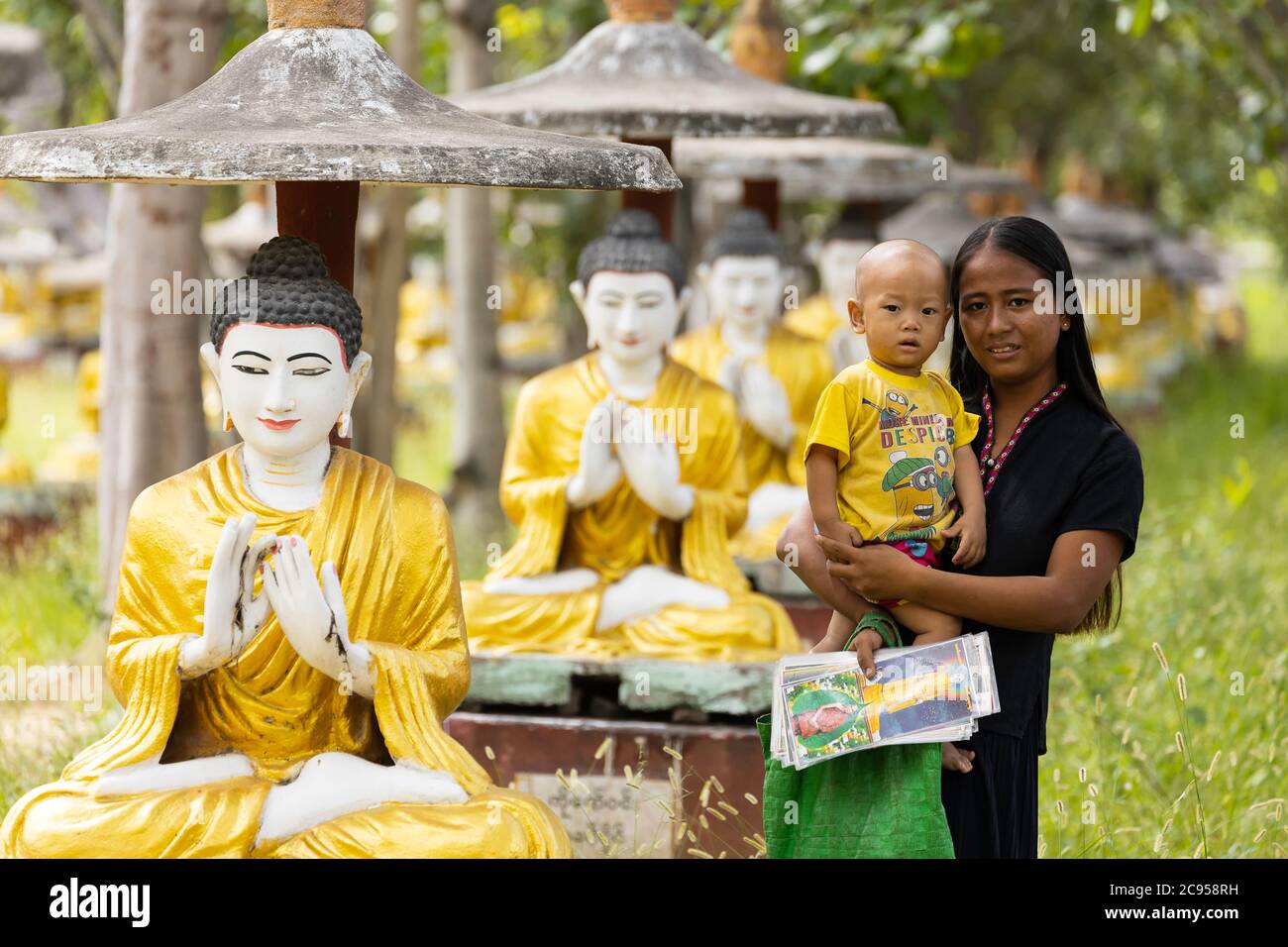 Sagaing/Myanmar-3 ottobre 2019: Una donna birmana tiene il suo bambino in attesa di vendere dipinti ai turisti in un tempio. Foto Stock