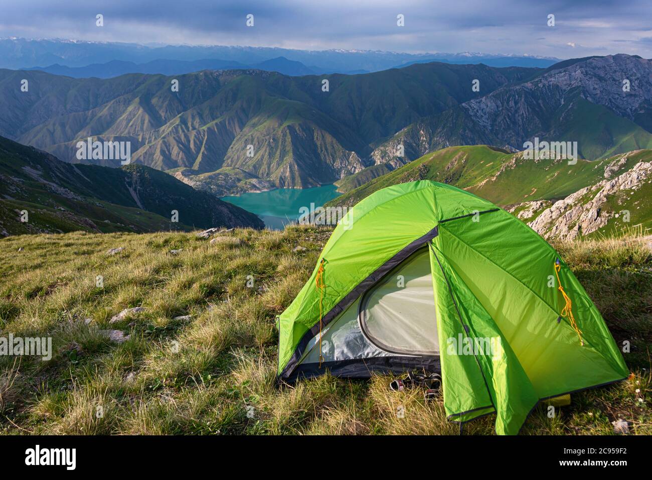 Idilliaco paesaggio estivo con sentiero escursionistico in montagna con bella tenda verde, pascoli di montagna, lago, cielo blu e nuvole. Tian-Shan, Kirghizistan Foto Stock