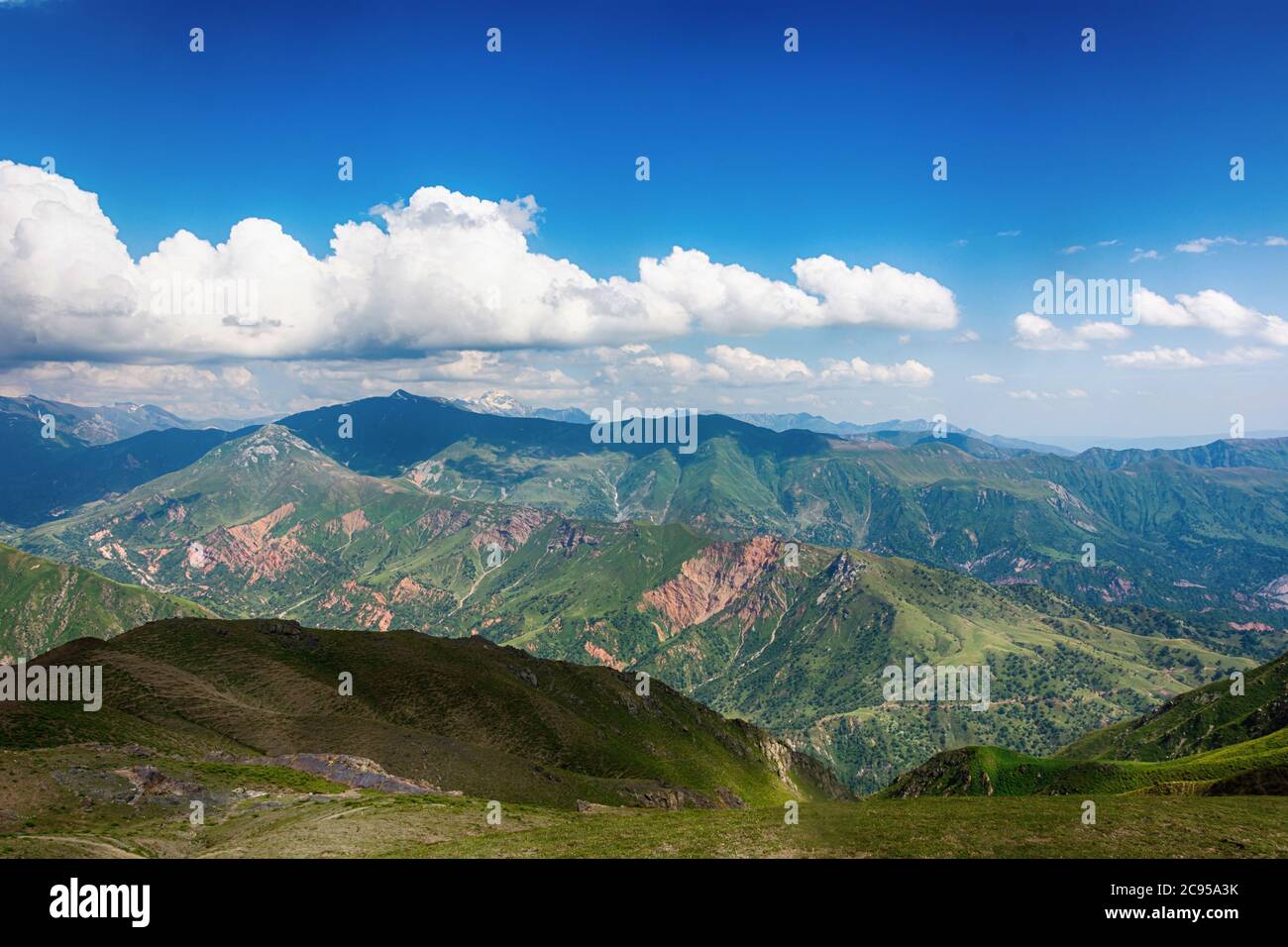 Idilliaco paesaggio estivo con sentieri escursionistici in montagna con bellissimi verdi pascoli di montagna, cielo blu e nuvole. Tian-Shan, Kirghizistan. Foto Stock