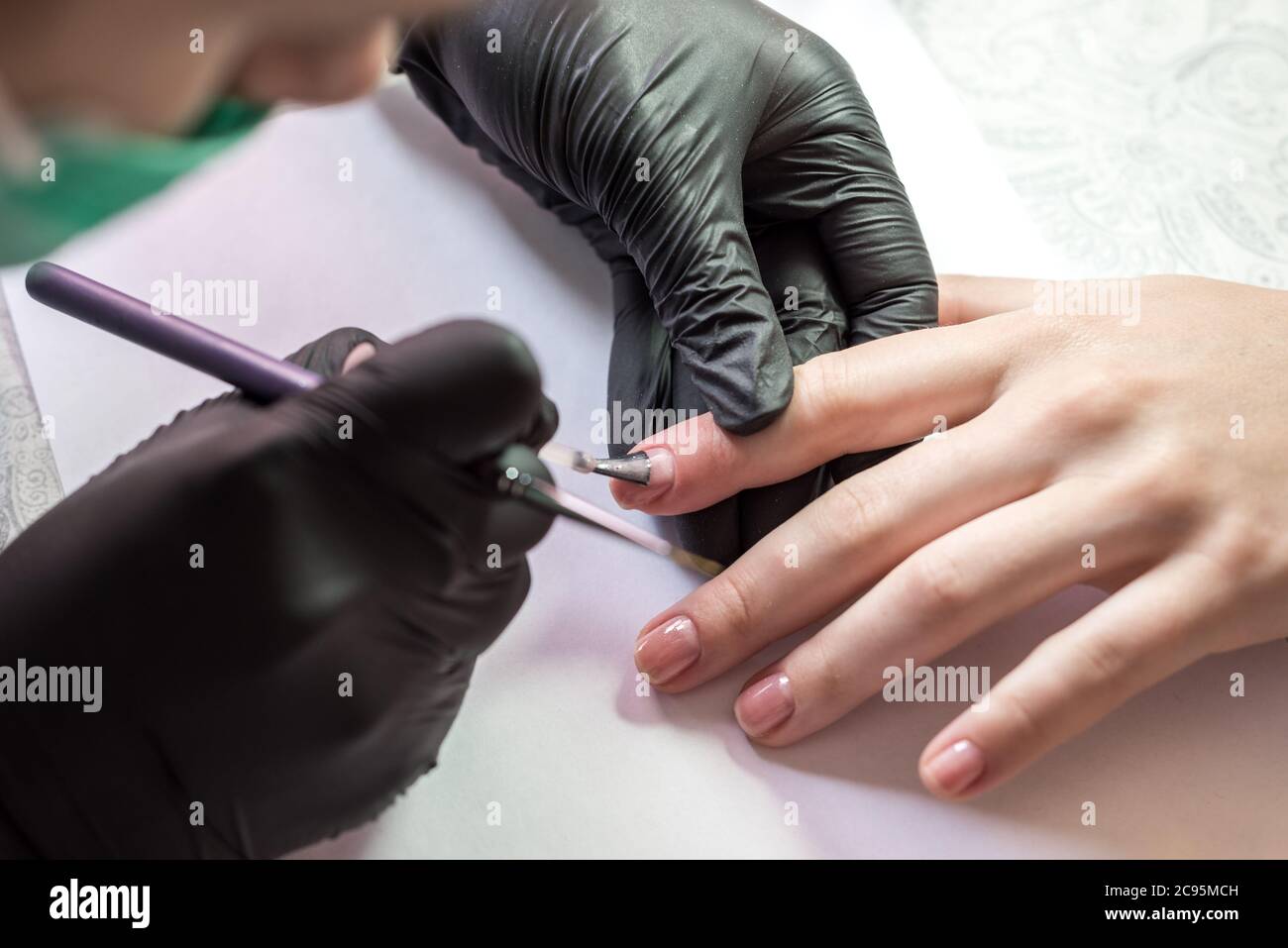 Il processo di creazione di una manicure. Primo piano di una donna in un salone. Estetista mette unghie su un cliente. Foto Stock
