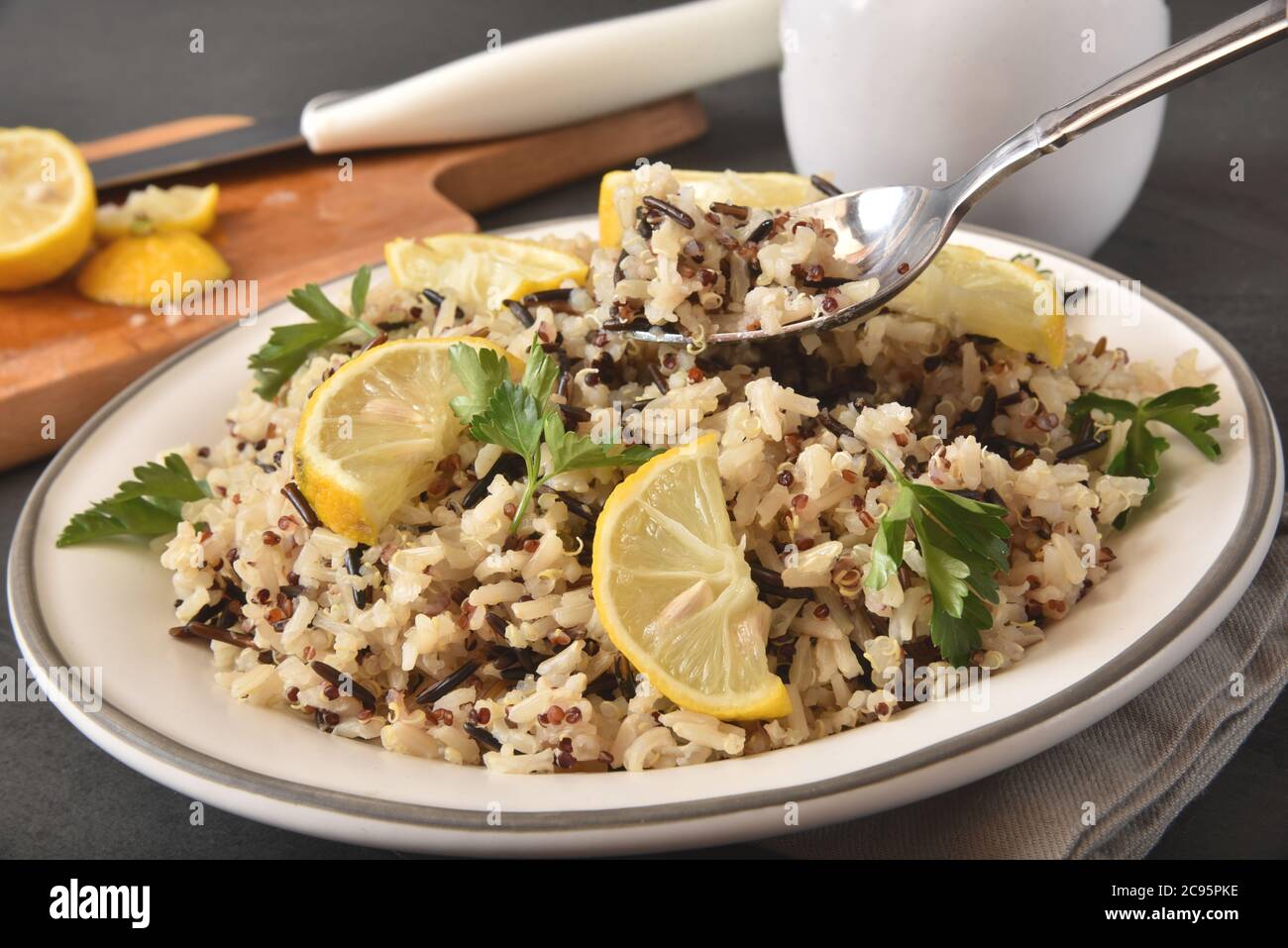 Sano pasto vegano di riso selvatico, riso bruno e tricolore quinoa servito con limone e coriandolo Foto Stock