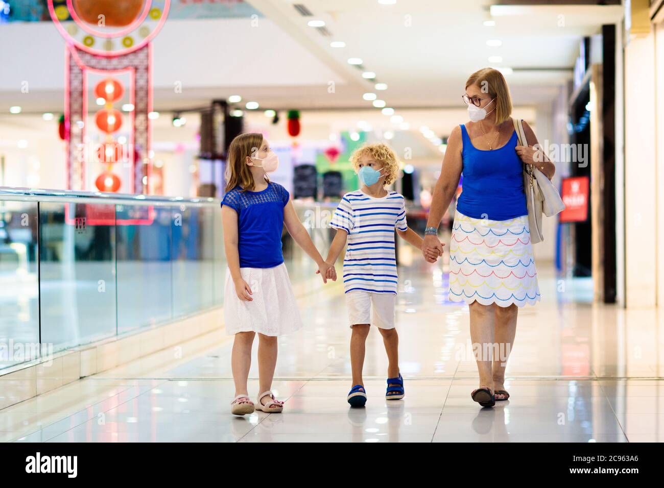 La famiglia indossa la maschera facciale nel centro commerciale in Asia. Madre e bambini indossano facemask durante il coronavirus e l'epidemia di influenza in Cina. Virus e malattia p Foto Stock