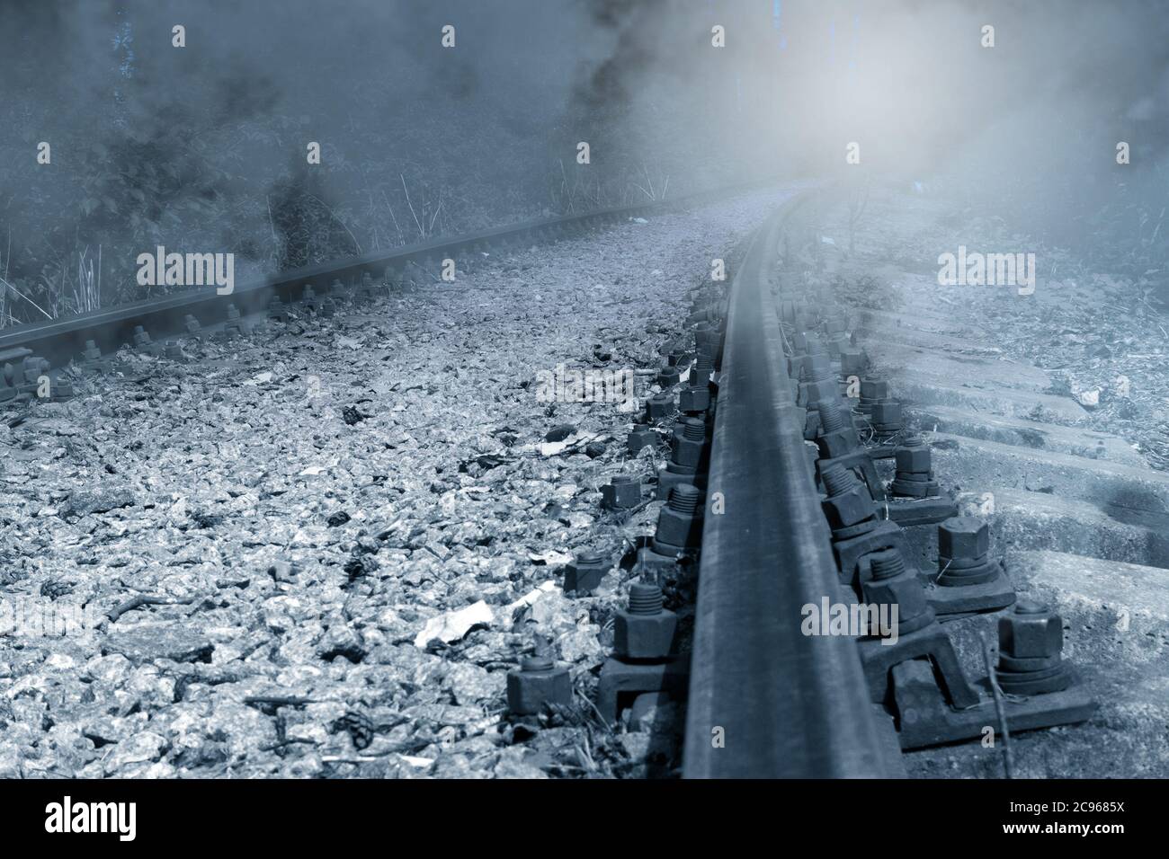 Vecchia ferrovia arrugginita abbandonata in nebbia che scava in lontananza per un giro con luce mistica, immagine monocromatica Foto Stock