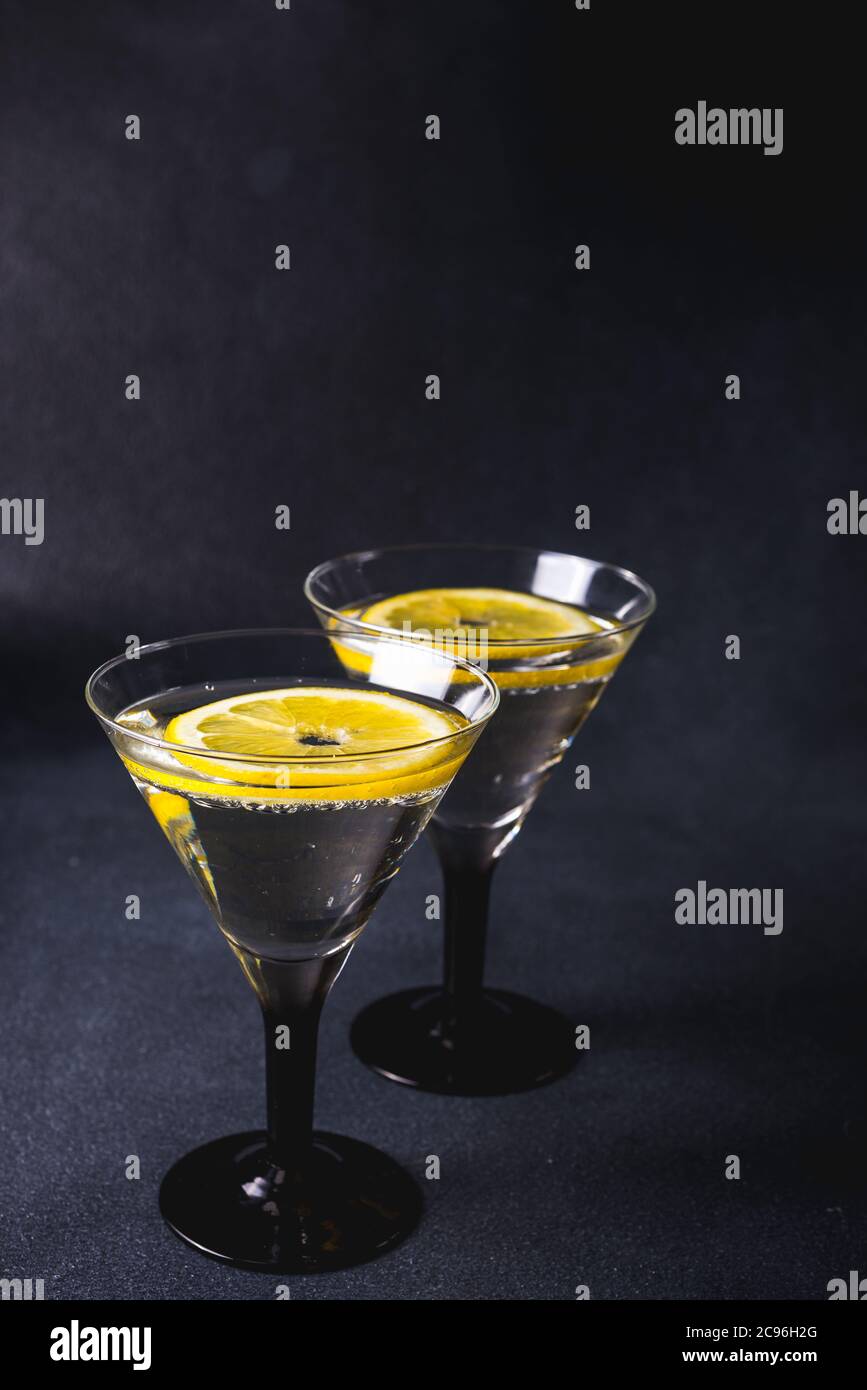 Cocktail alcolico con splash. martini secco con olive nere. Cocktail Vermouth all'interno del bicchiere martini su sfondo scuro. I bicchieri Martini sono al bar. Foto Stock